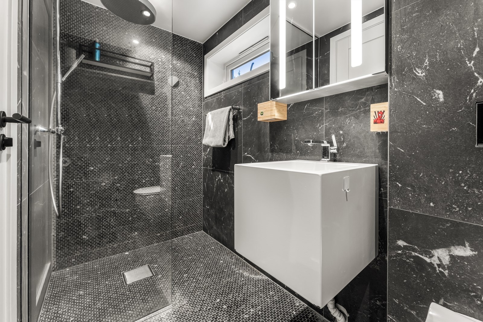 Badet er innredet med vegghengt wc, dusj med vegg i herdet glass, samt servantinnredning og overskap Galleribilde