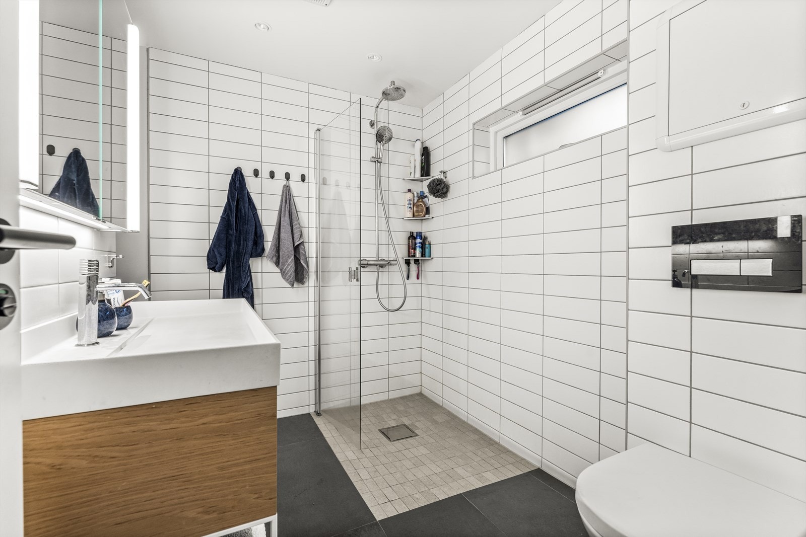 Flislagt baderom i utleiedelen m/vegghengt wc, dusj m/dør i herdet glass, servantinnredning og overskap Galleribilde