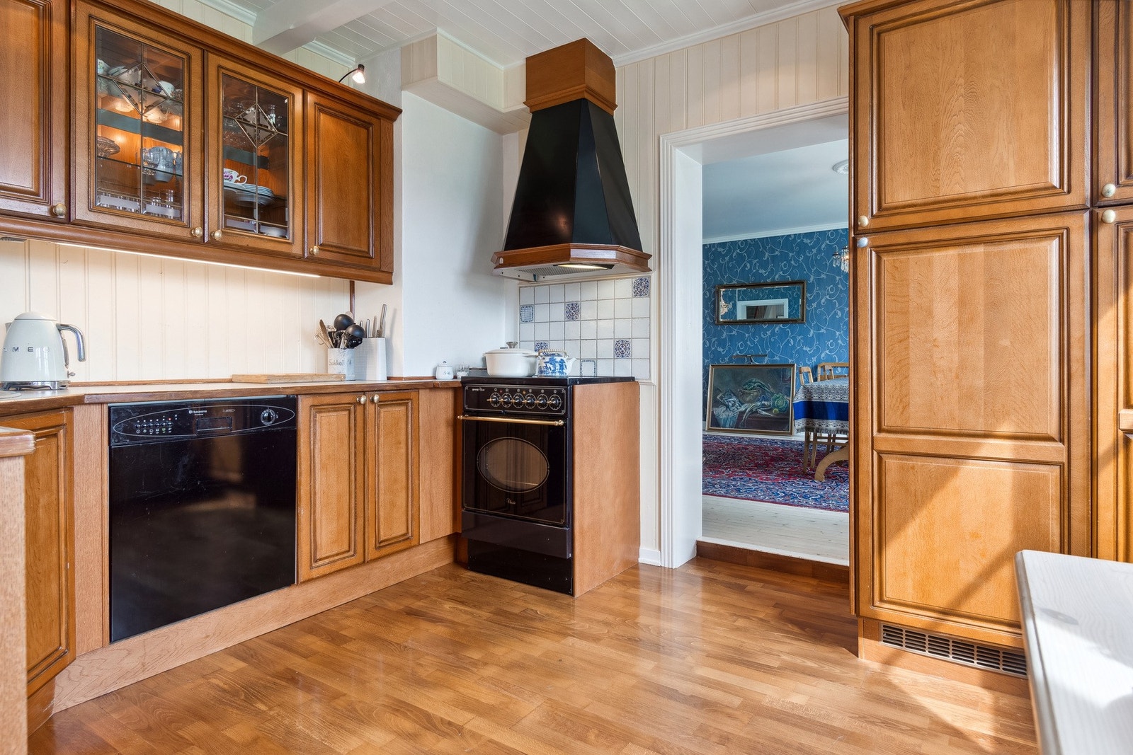 Kjøkken med oppvaskmaskin, komfyr og Røroshetta. Glassdører i innredning. Galleribilde