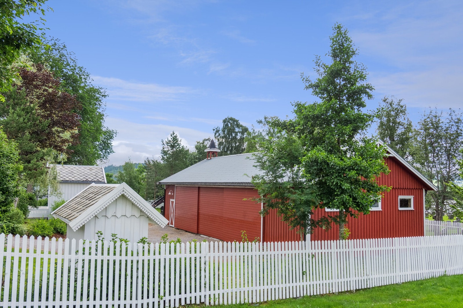 Redskapshus og øvrige bygninger. Hvitt stakittgjerde mot kirkegården. Galleribilde