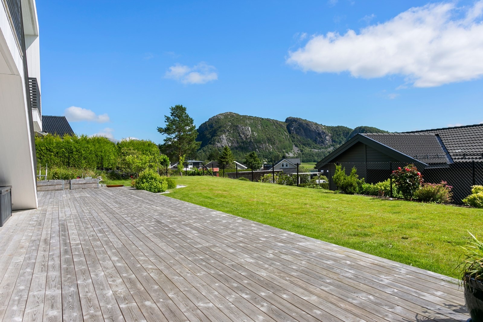 Tomten er innegjerdet og pent opparbeidet med plen og diverse beplantning Galleribilde