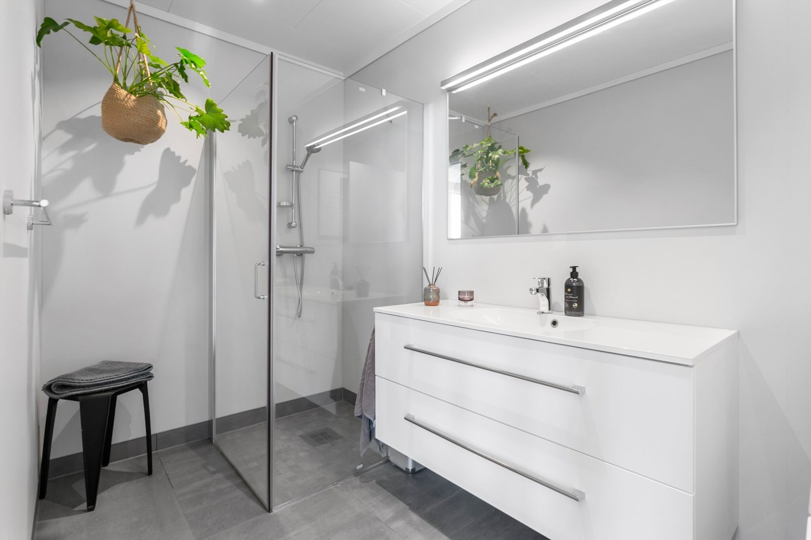 Flott bad som har flis på gulv, våtromsplater på vegger og malt himling - badet er utstyrt med dusjvegger, innredning m/komposittplate og vask fra Linnbad, speil med lys samt wc Galleribilde