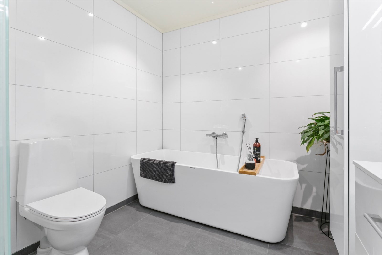 Flott bad som har fliser på gulv, våtromsplater på vegger og malt himling Galleribilde