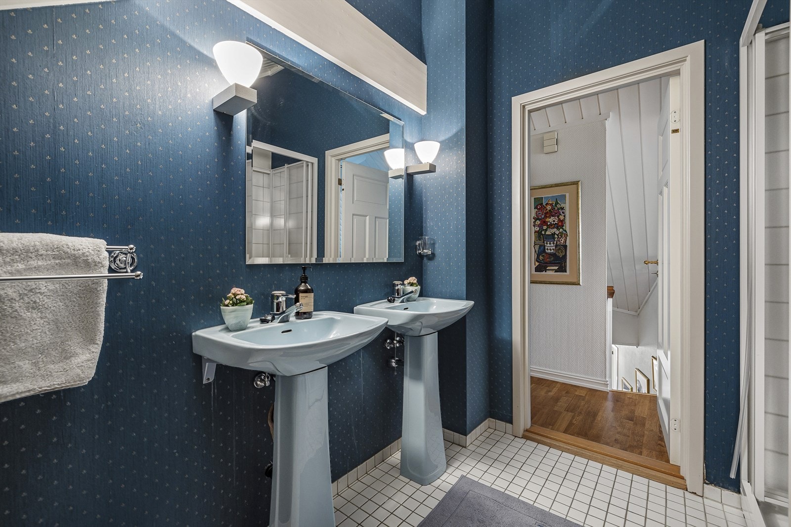 Bad innredet med dusjkabinett, to søyleservanter og gulvmontert toalett Galleribilde