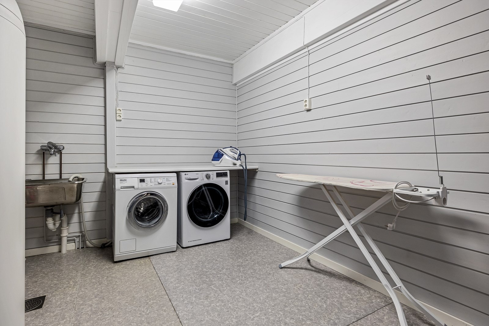 Vaskerom i underetasjen. Rommet er innredet med skyllekar, benk og opplegg for vaskemaskin og tørketrommel Galleribilde