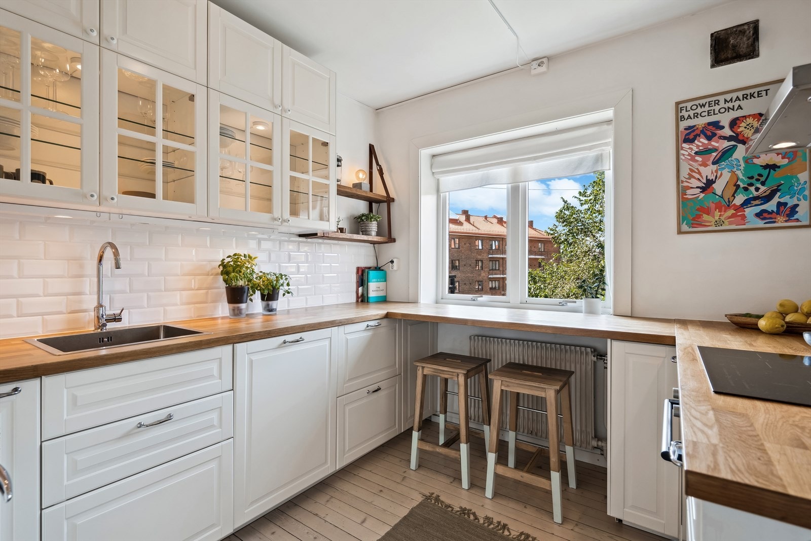 Innredningen består av hvite profilerte fronter, flere overskap med fronter i glass, benkeplater i heltre/spon, rustfri oppvaskkum, ventilator med kullfilter og fliser over benkeskap. Galleribilde