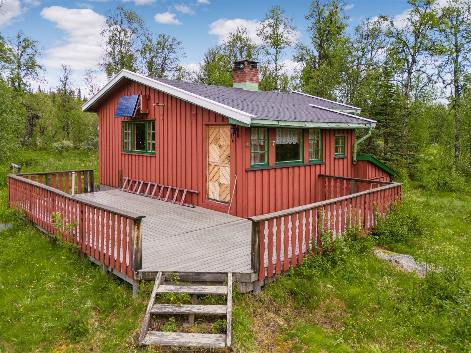 Sjarmerende rød hytte med stor terrasse, idyllisk beliggende i naturskjønne omgivelser. Perfekt for friluftsentusiaster og naturelskere. Galleribilde