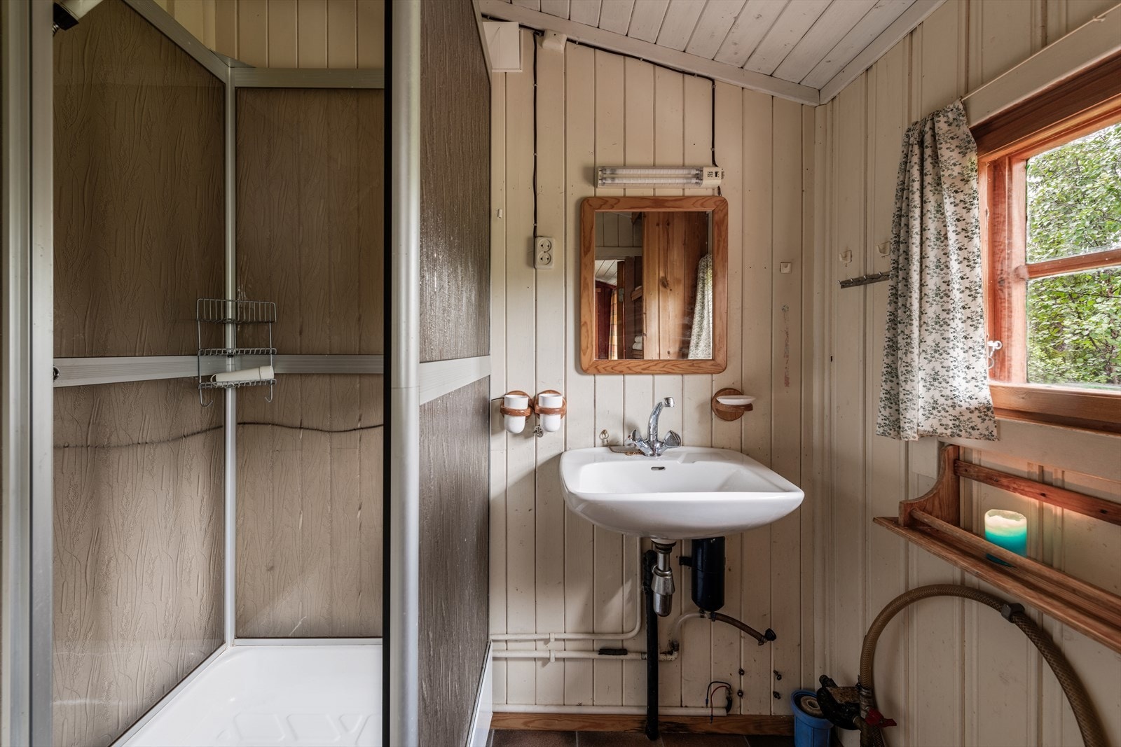 Lyst baderom med dusjkabinett, servant og vindu som slipper inn naturlig lys. Galleribilde