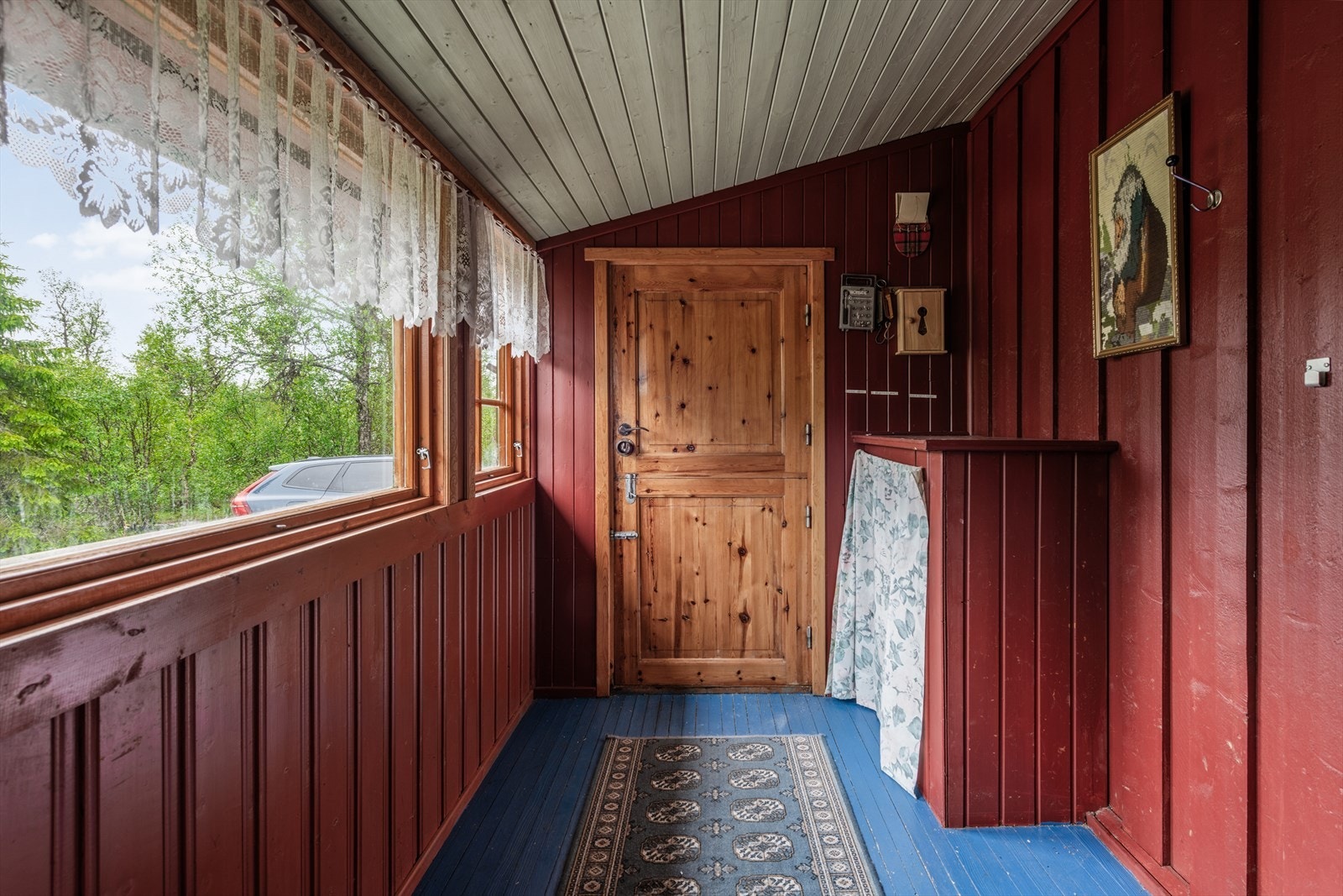 Hyggelig inngangsparti med klassisk treverk og utsikt mot grøntområder. Fine detaljer som gir et varmt velkomstinntrykk. Galleribilde