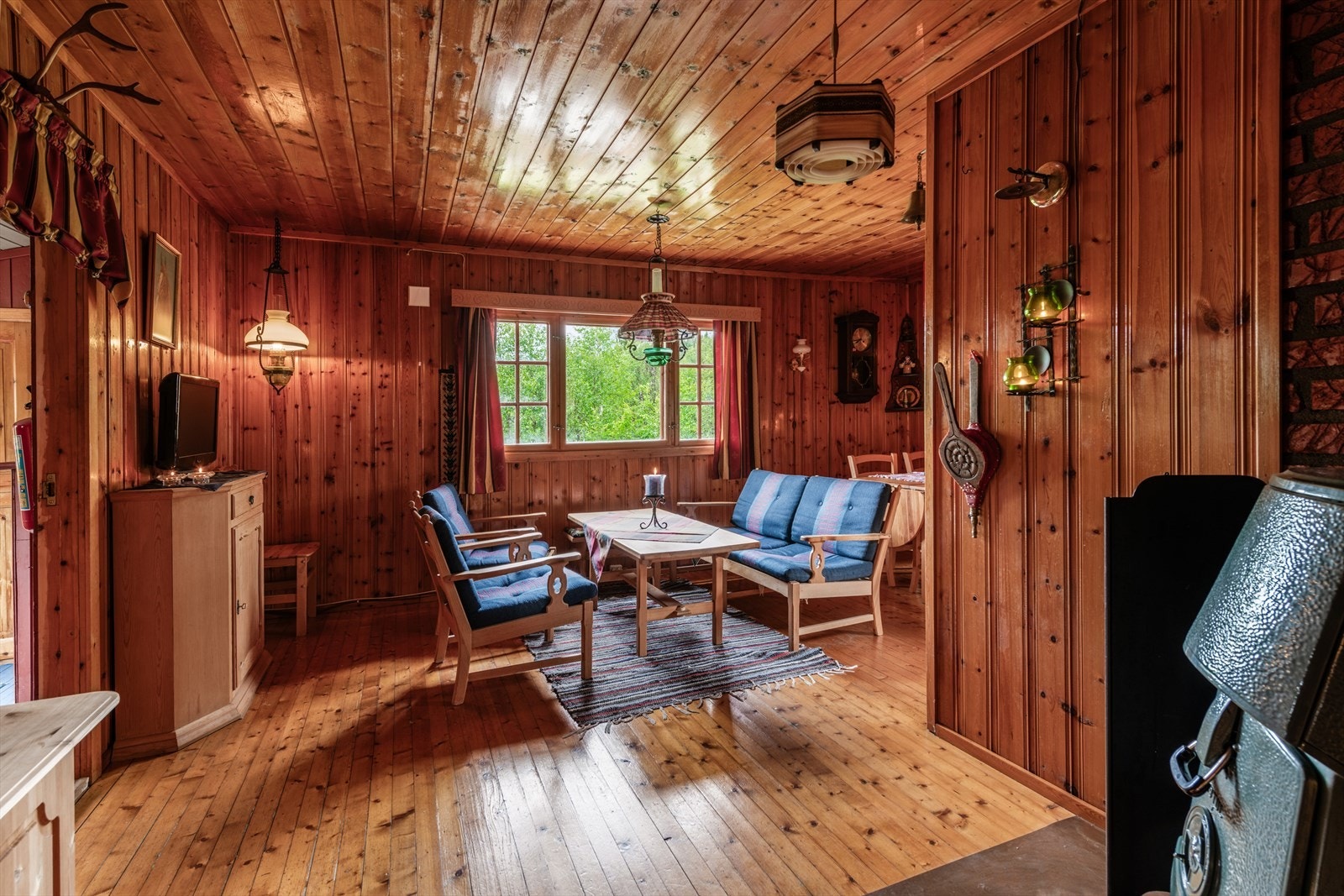 Stue med hyttestil med naturlig lys og trepanelvegger. Perfekt for avslapning og hyggelige sammenkomster. Galleribilde