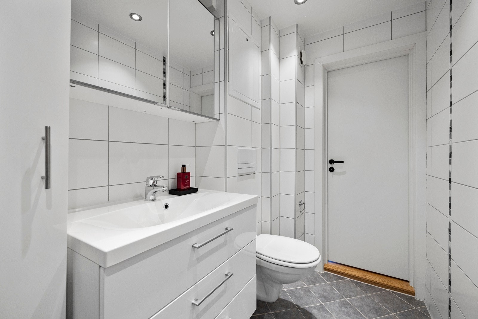 Badet har vegghengt servant med speil, samt vegghengt klosett med sisterne. Galleribilde