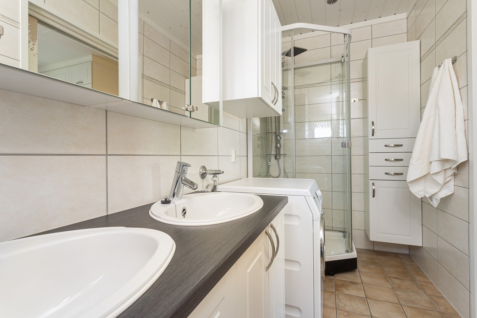 Badet er innredet med toalett, dobbel servant, dusjkabinett og har opplegg for vaskemaskin. Galleribilde