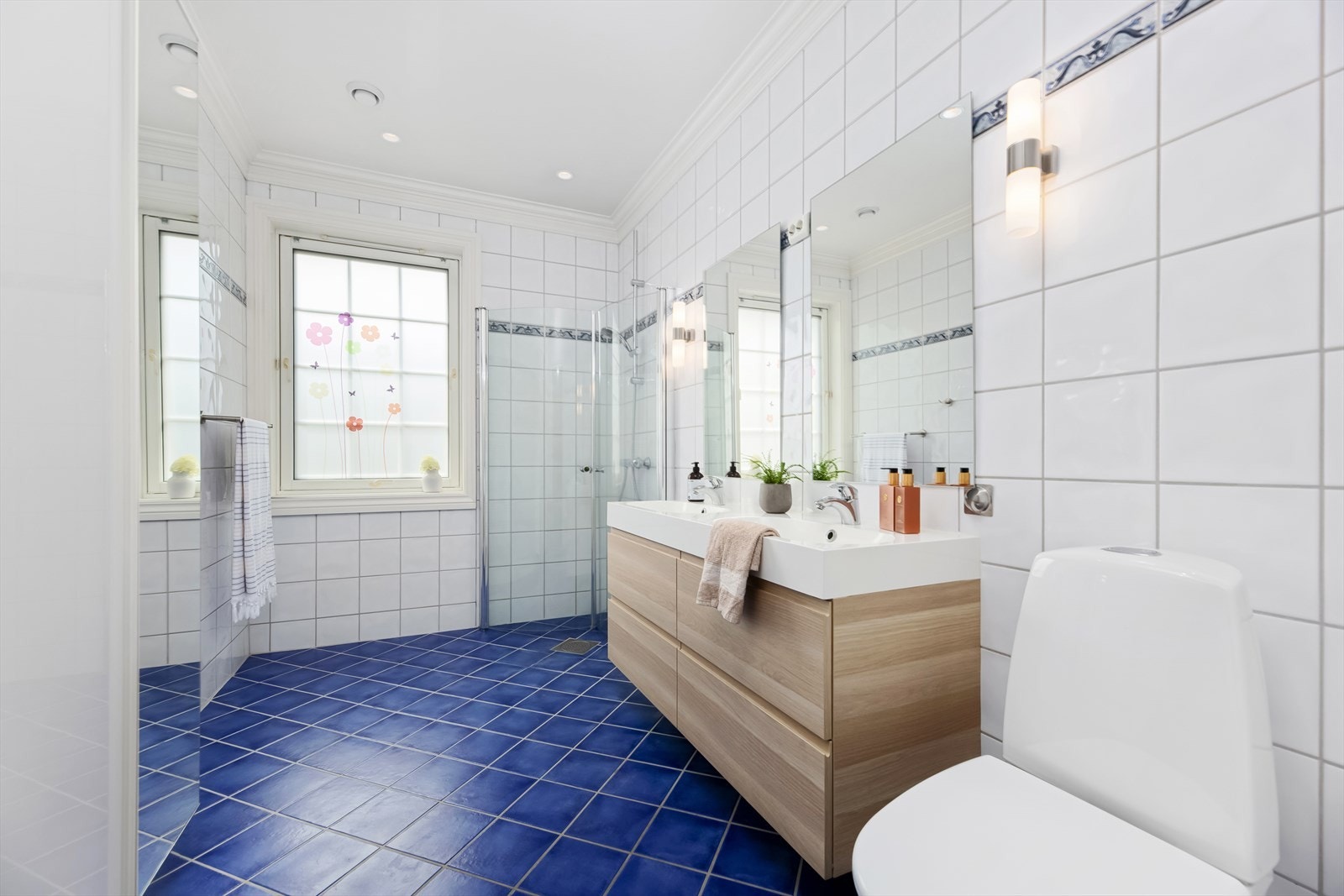 Badet er innredet med baderomsinnredning med to servanter, speil og vegglamper. Galleribilde