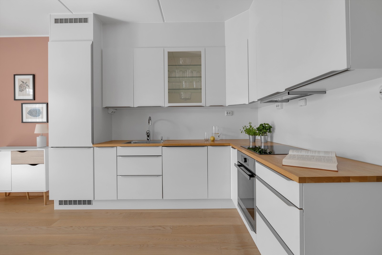 Moderne og pent kjøkken med hvite slette fronter, skjulte gripelister og benkeplate i heltre Galleribilde