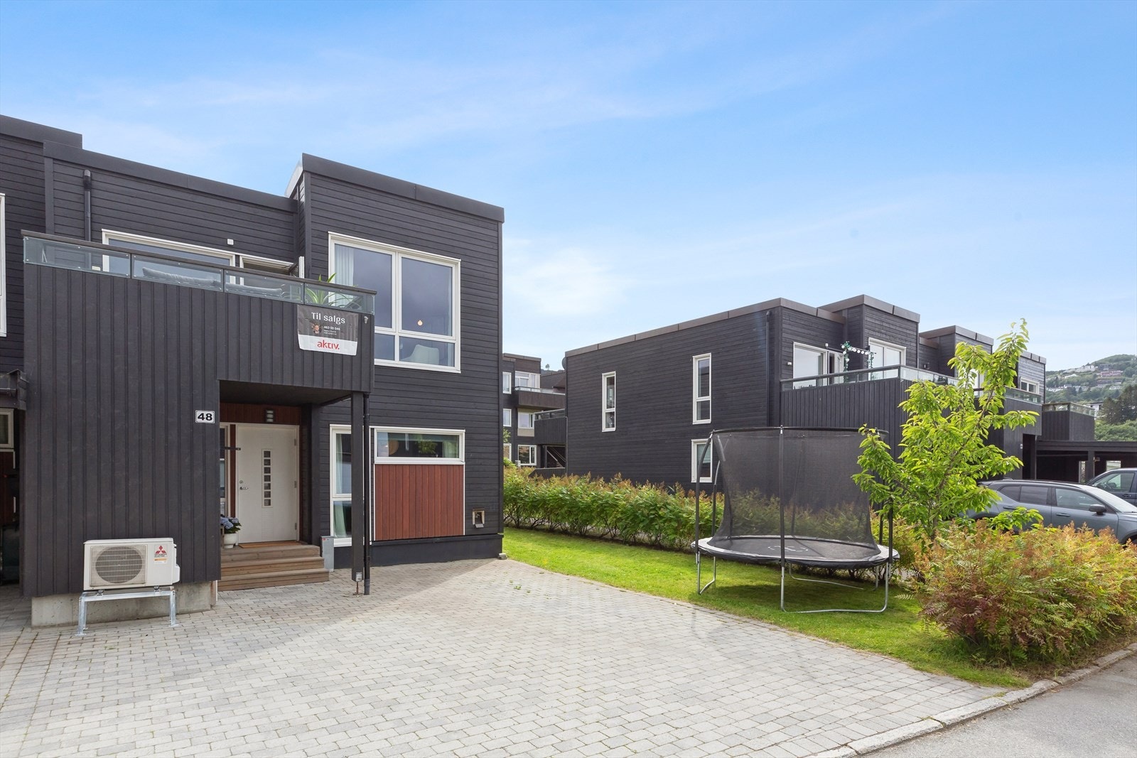 Bilen parkeres på en steinlagt gårdsplass med elbillader montert i 2022. Galleribilde