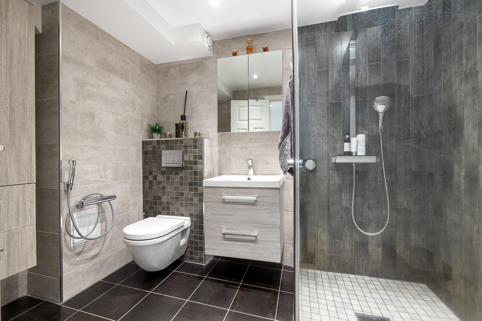 Badet ble pusset opp i 2015, og fremstår som delikat og moderne med fliser i gråtoner på veggene og koksgrå fliser fra 2018 på gulv med gulvvarme. Galleribilde