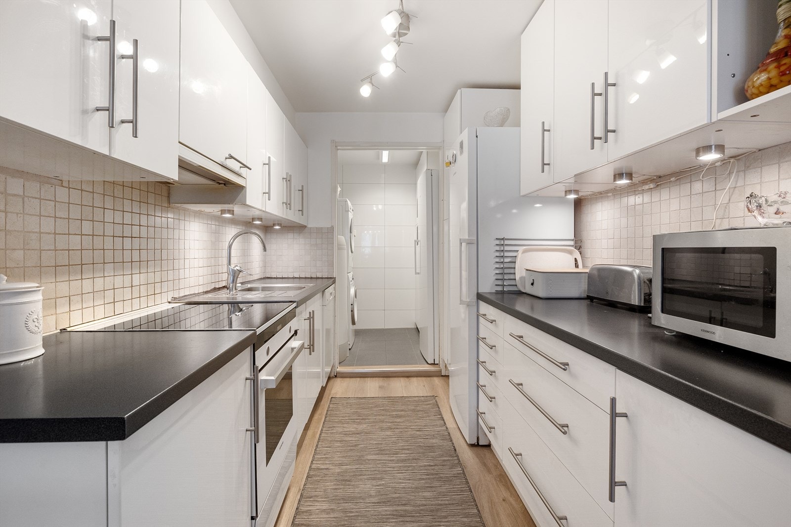 Innredningen har hvite høyglansfronter og koksgrå laminatbenkeplate med nedfelt kum i stål. Galleribilde