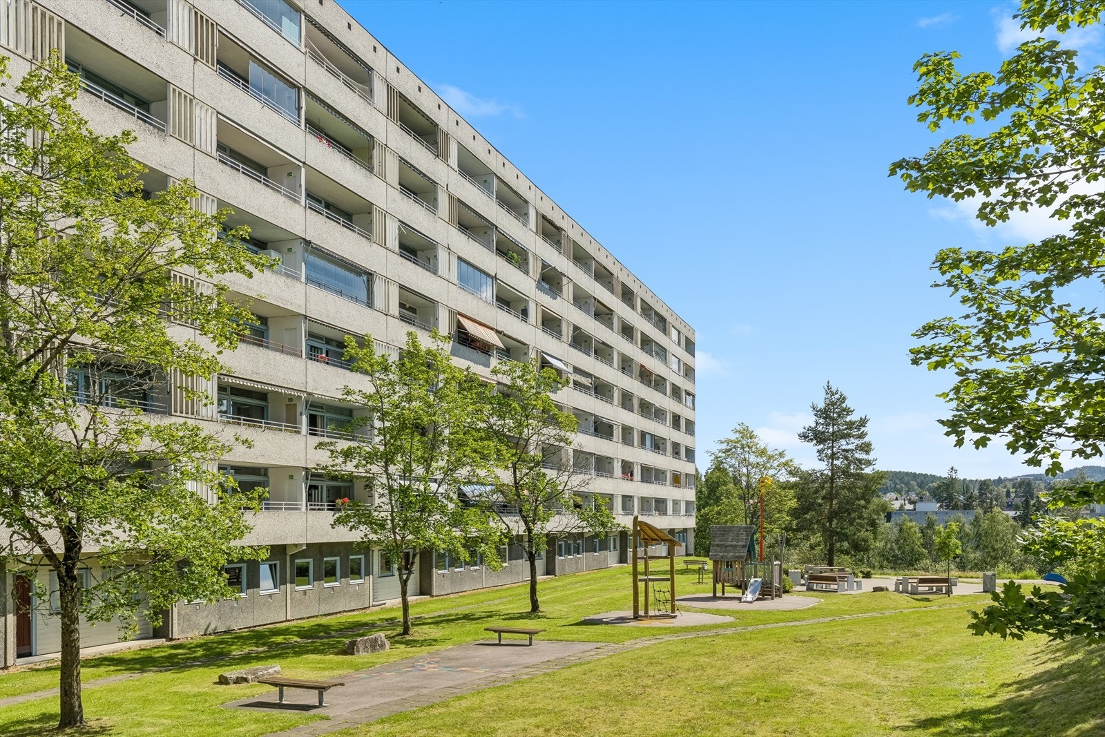 Pent opparbeidet fellesområde med benker, lekeplass og grøntområde. Galleribilde