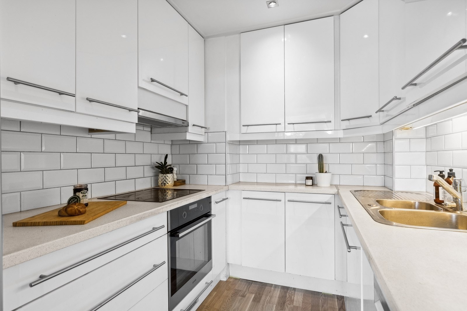 Kjøkkeninnredningen består av glatte fronter, integrert komfyr og platetopp, laminat benkeplate og fliser mellom over- og underskap. Galleribilde