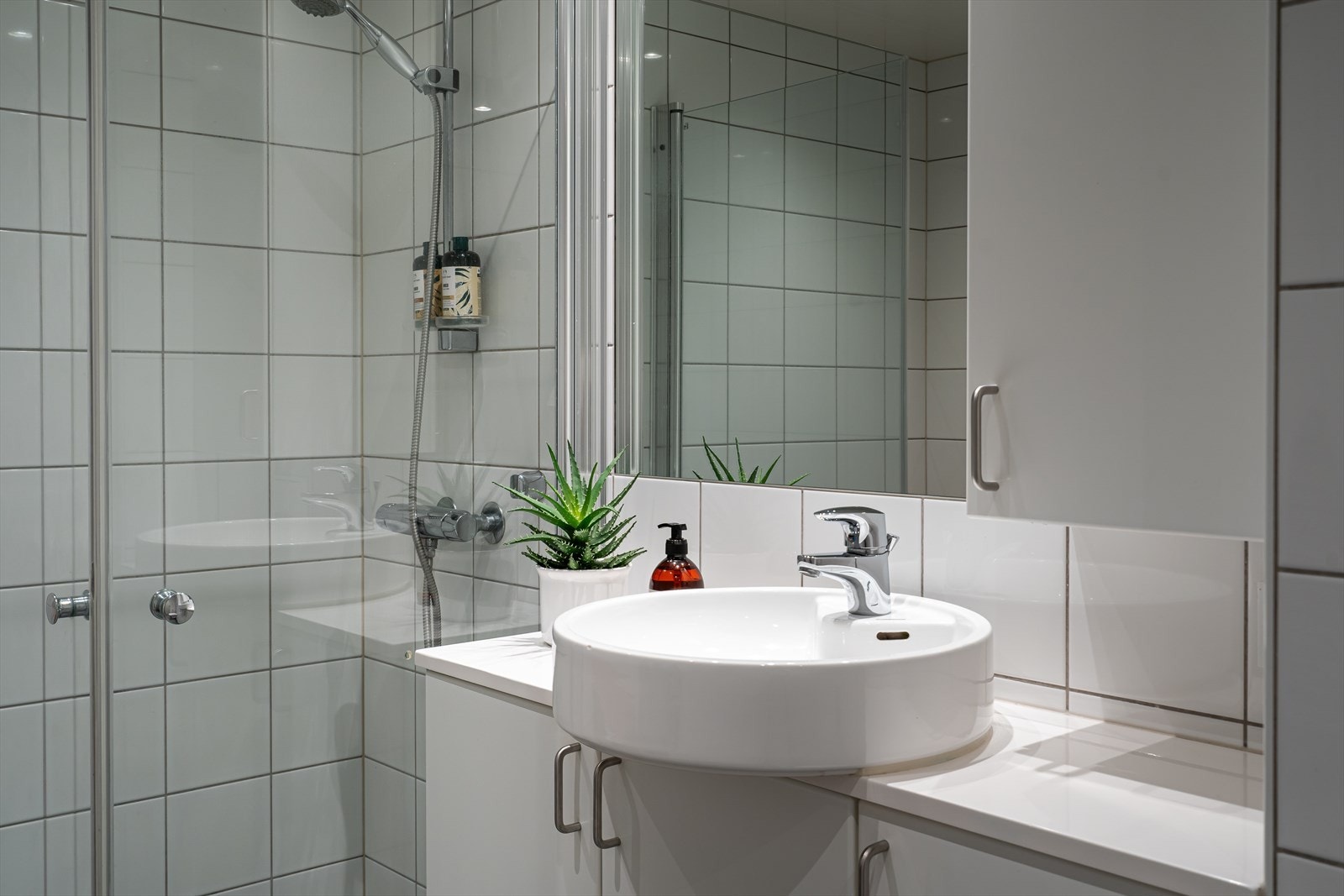 Dusjhjørne med innfellbare dusjvegger, vegghengt toalett og tidløs innredning med servant. Rommet er av god størrelse, så her er det plass til ekstra oppbevaring. Galleribilde