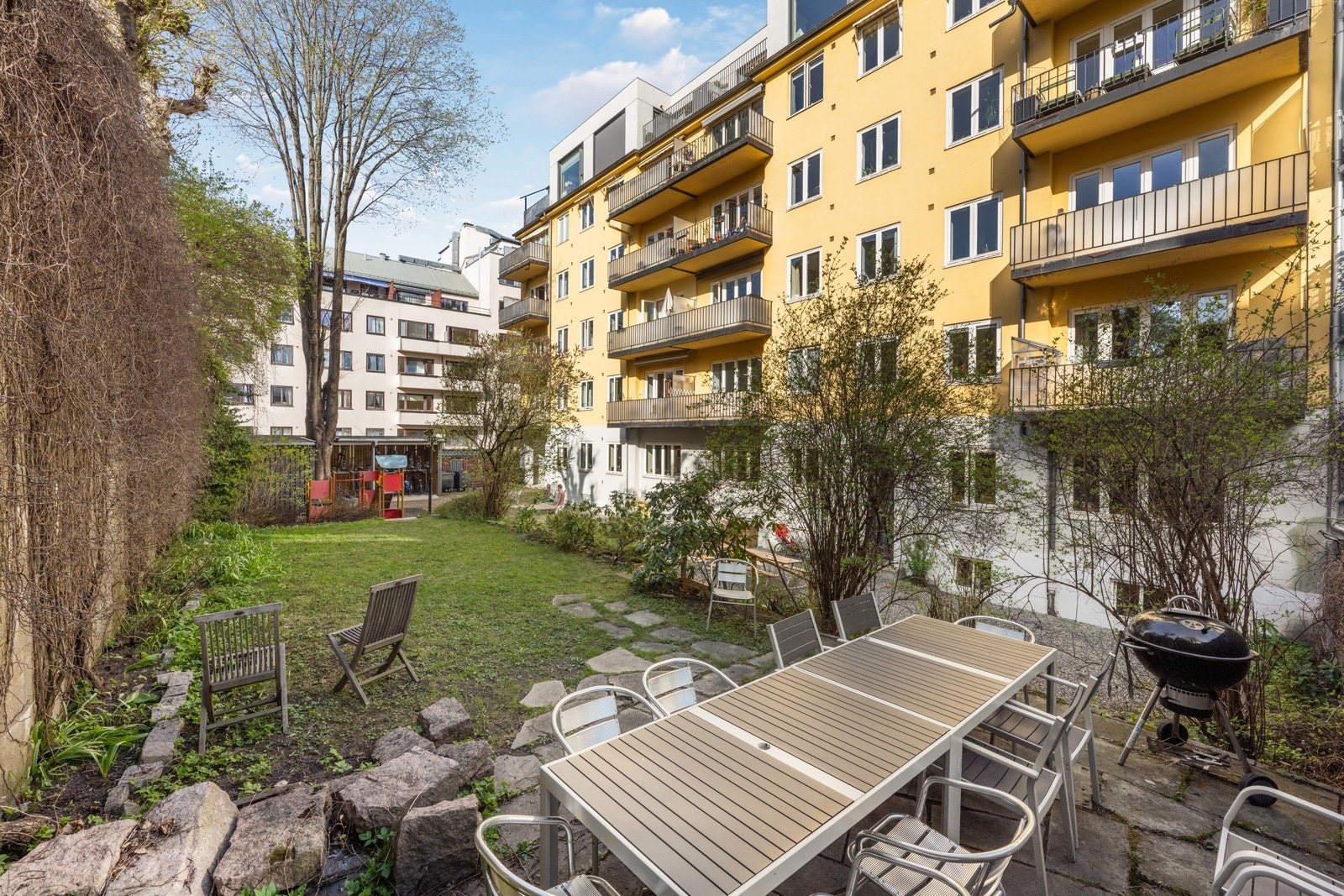 Usjenert og barnevennlig bakgård med lekestativ og to sykkelboder Galleribilde