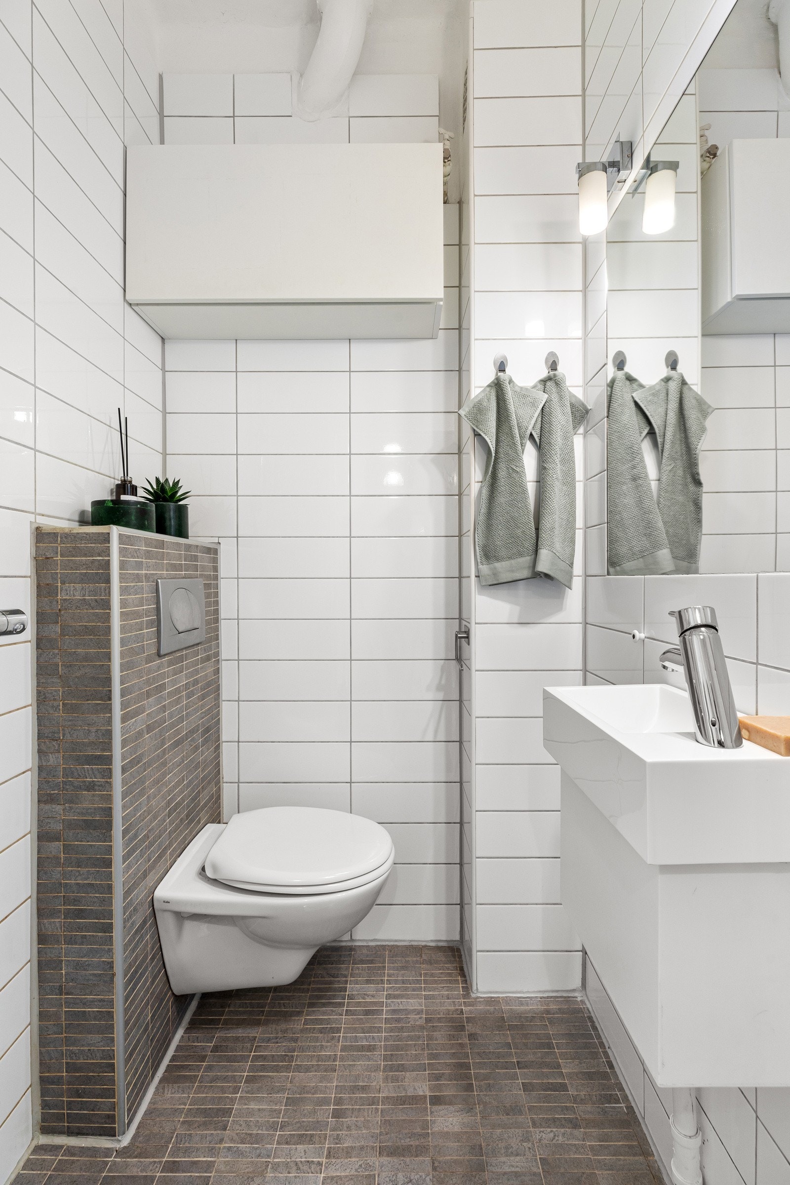 Rommet byr på varmekabler, servant med skap under og speil, vegghengt klosett og dusjsone med forheng. Galleribilde