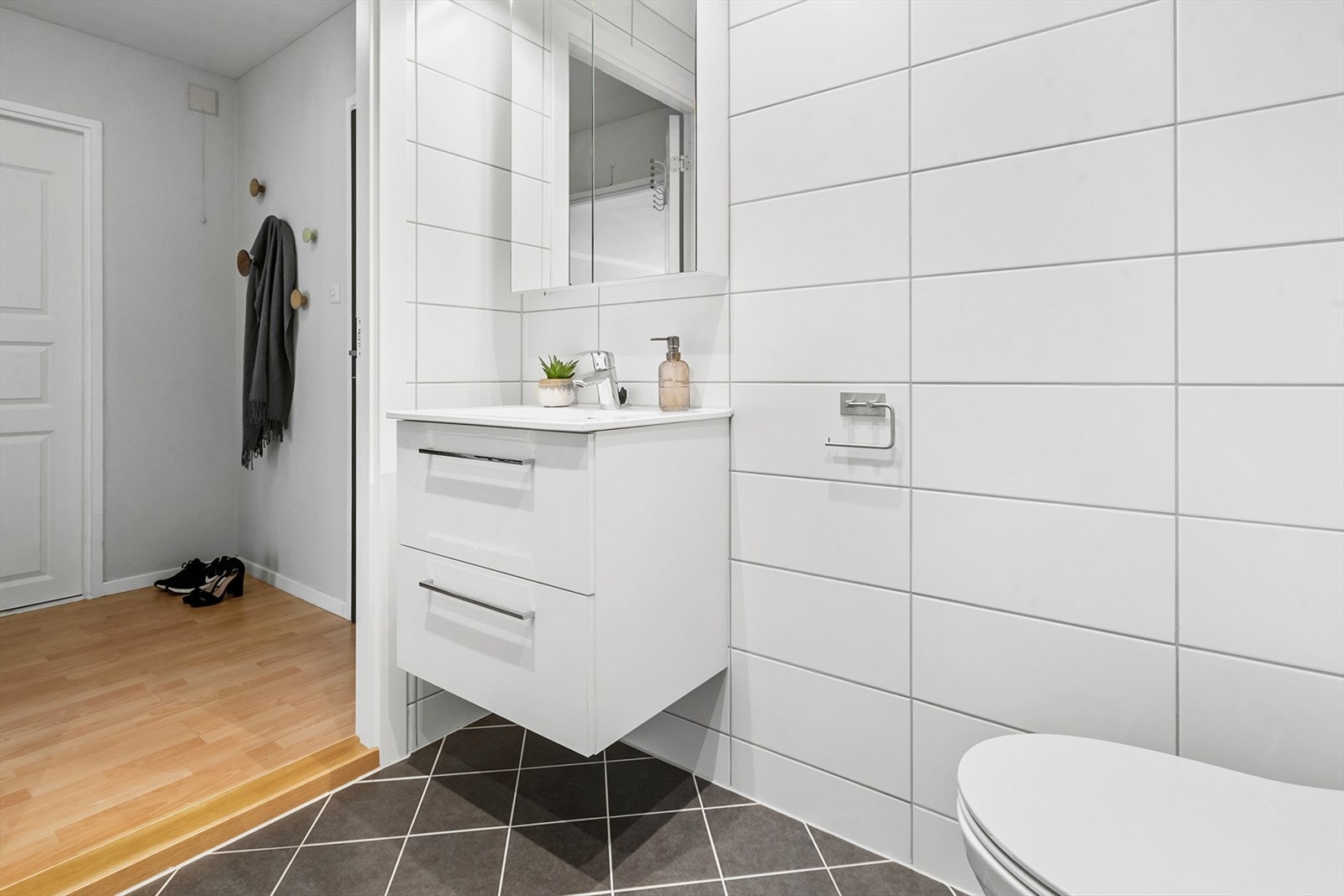 Badet har moderne standard og er innredet med servant i underskap, speilskap med lysarmatur, dusjhjørne, vegghengt toalett og opplegg for vaskemaskin. Galleribilde