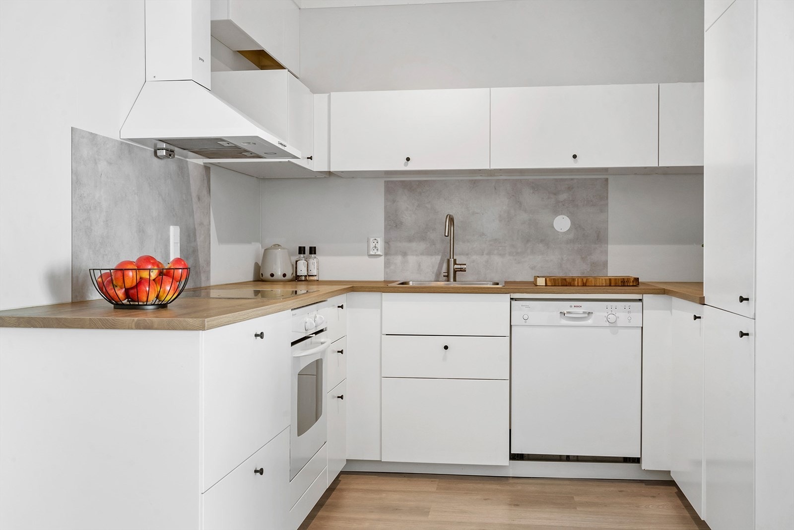 Kjøkkenet er lyst og effektiv utformet med innredning på tre vegger. Kjøkkeninnredningen ha malte fronter av finér og lamintert benkeplate. Galleribilde