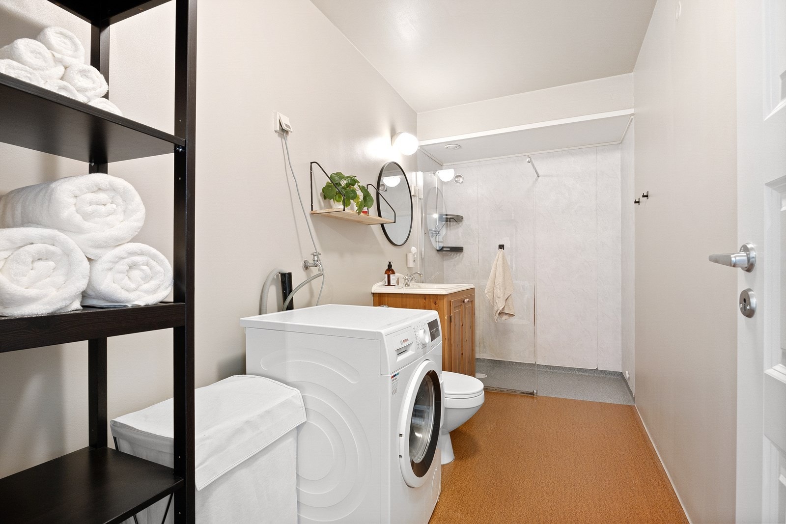Badet er romslig og inneholder toalett, dusj med glassvegg, speil, baderomsinnredning med heldekkende servant og opplegg for vaskemaskin/tørketrommel Galleribilde