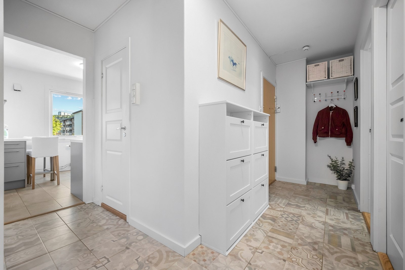 Leiligheten har en innbydende gang med fliser på gulv og flere muligheter til oppbevaring. Galleribilde