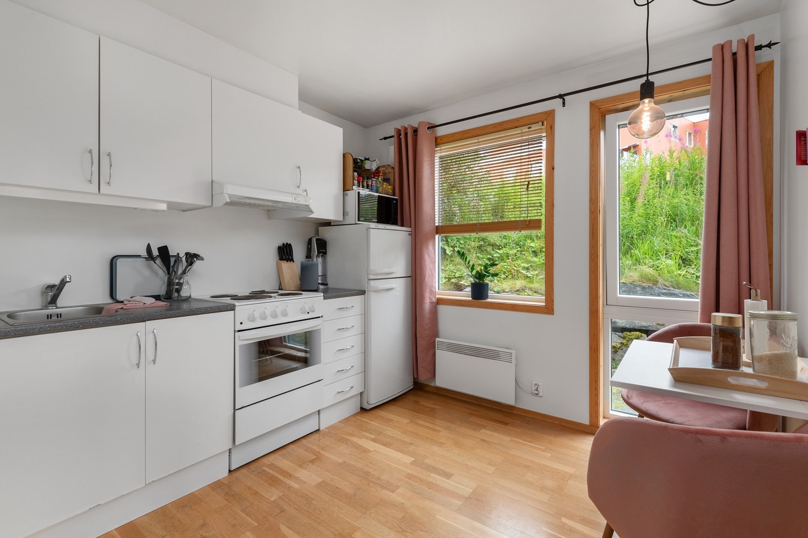 Kjøkkenet ligger adskilt til, og har hvite, slette fronter og godt med skap- og benkeplass. Her kan man enkelt innrede med et spisebord med klaff eller ileggsplate slik at det kan gjøres større ved behov. Galleribilde