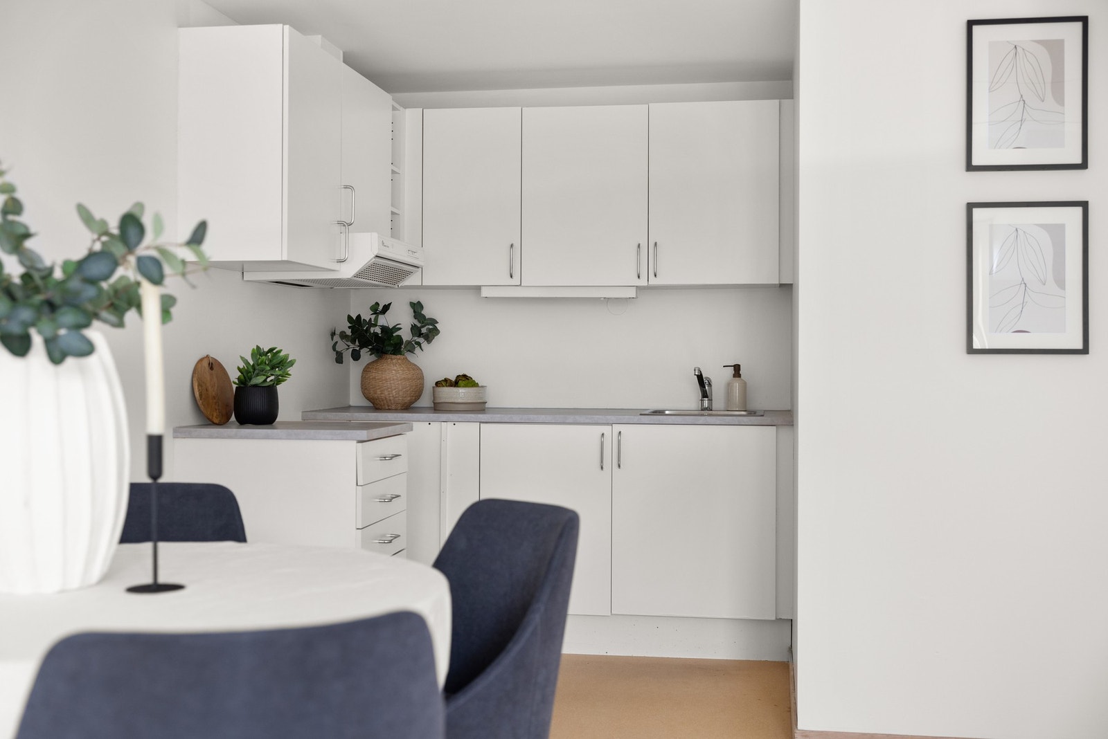 Kjøkkeninnredningen fremstår som tidløs og består av foliert glatt innredning, armatur, laminat benkeplate med nedfelt stålkum, nisje til komfyr. Galleribilde