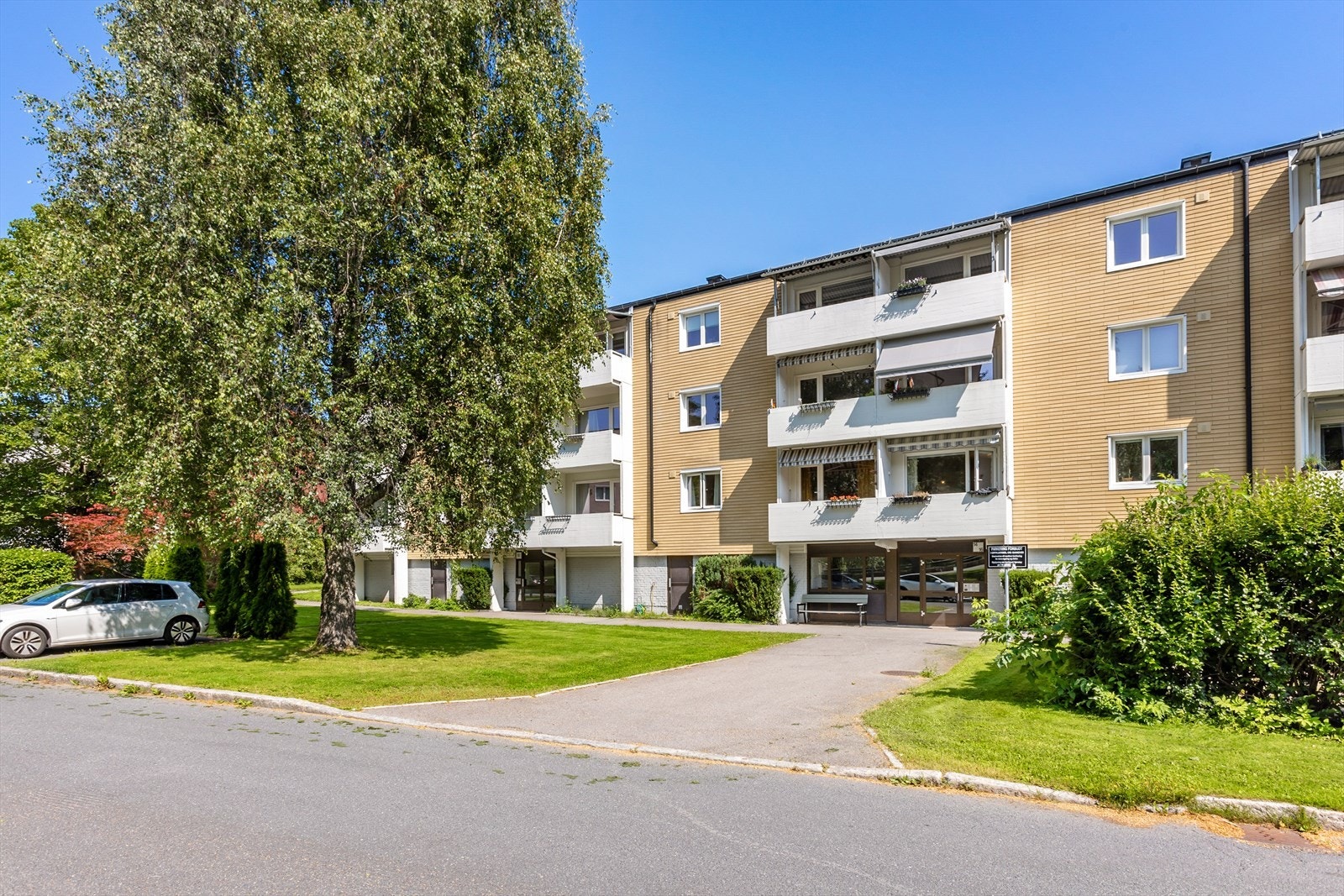 Velholdt boligblokk med grønne omgivelser og parkering. Galleribilde