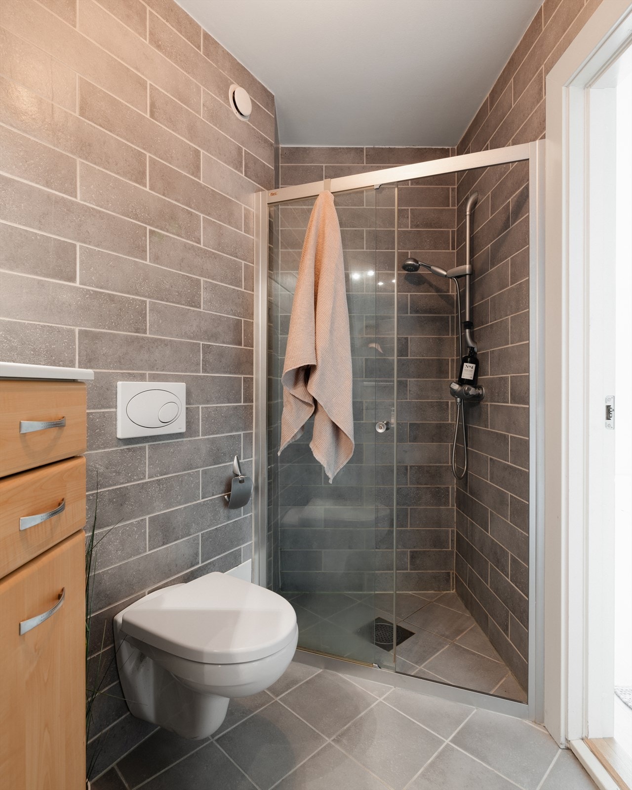 Innredningen består av servantskap, speil, vegghengt toalett og dusjnisje med skyvedør Galleribilde