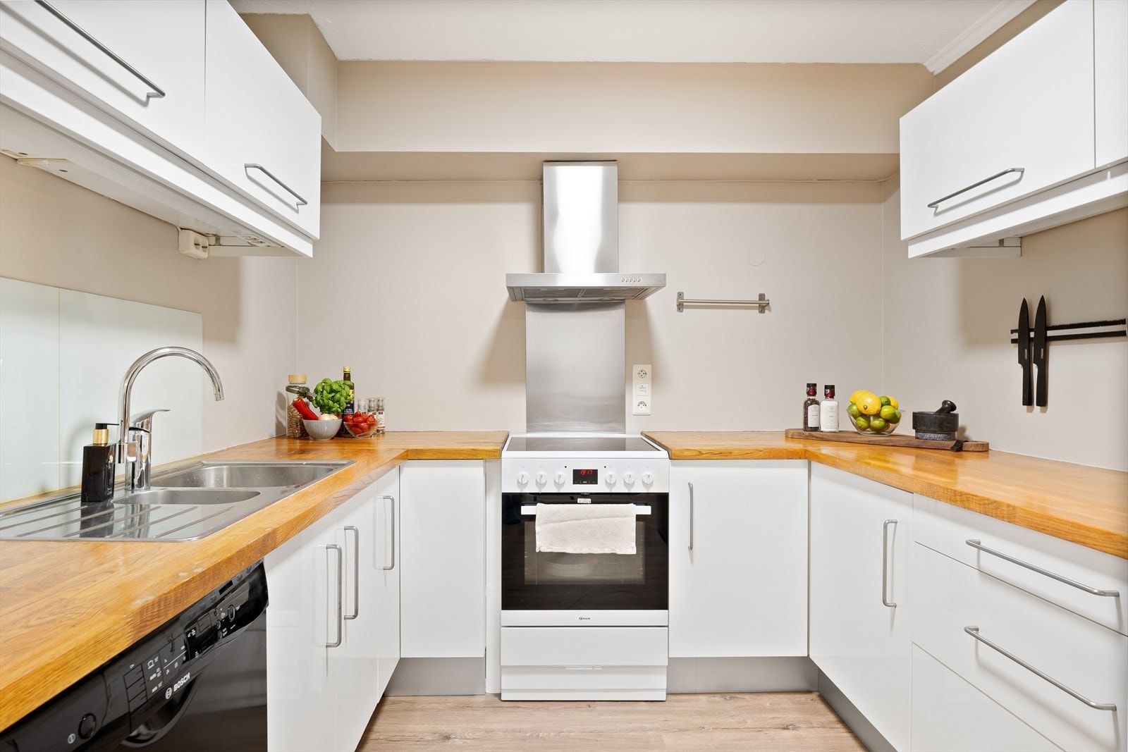 Kjøkkenet er stilrent utformet med hvite, glatte fronter og en benkeplate i tre. Galleribilde