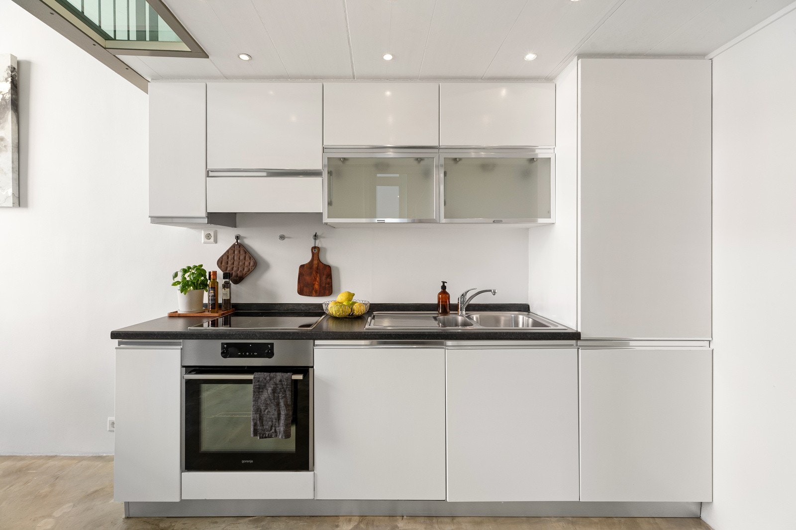 Åpen kjøkkenløsning med lekkert Italiensk kjøkkeninnredning og overskap med slette fronter, og benkebelysning Galleribilde