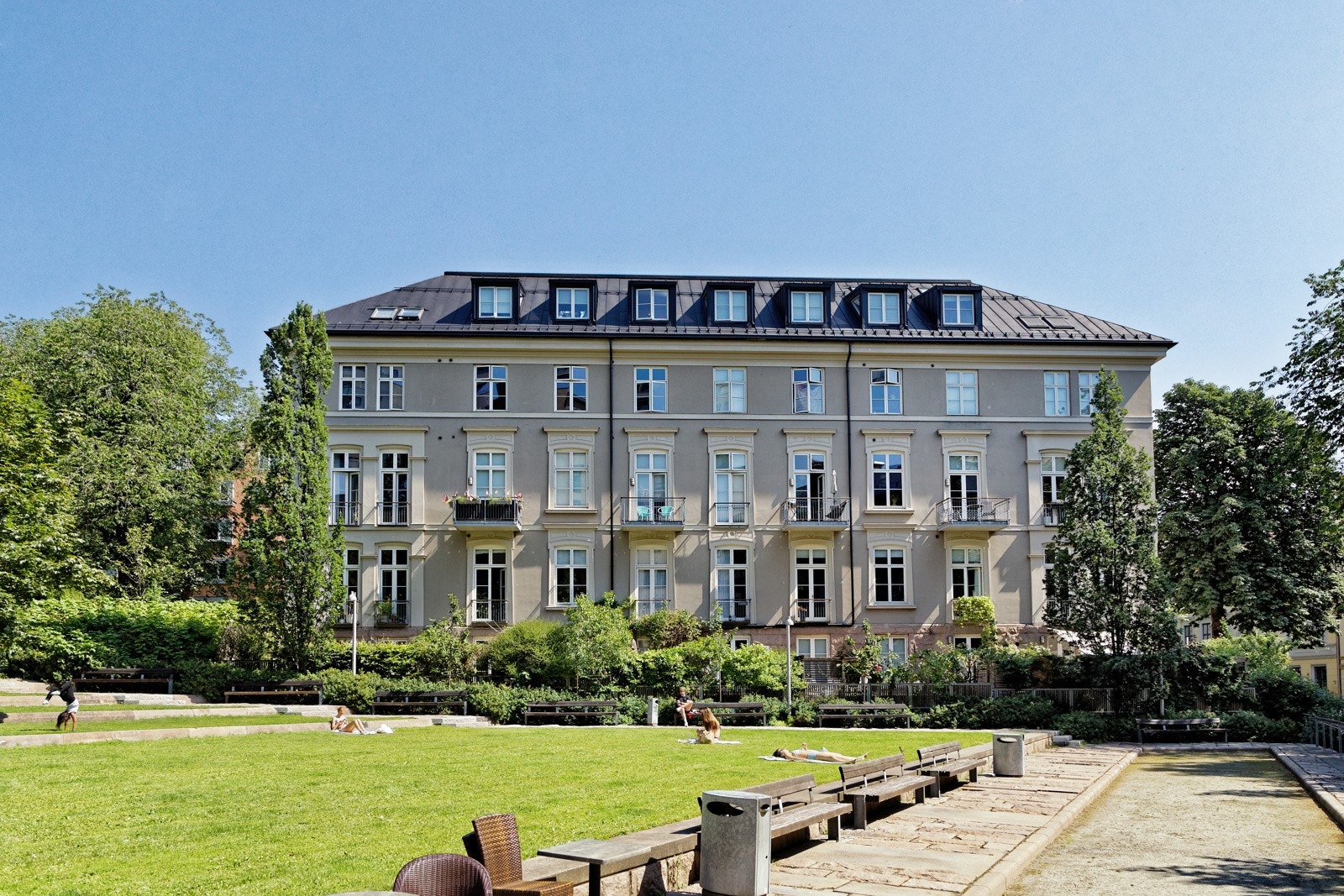 Tomten grenser til et større grøntområde med blant annet sittegrupper og gressplener Galleribilde