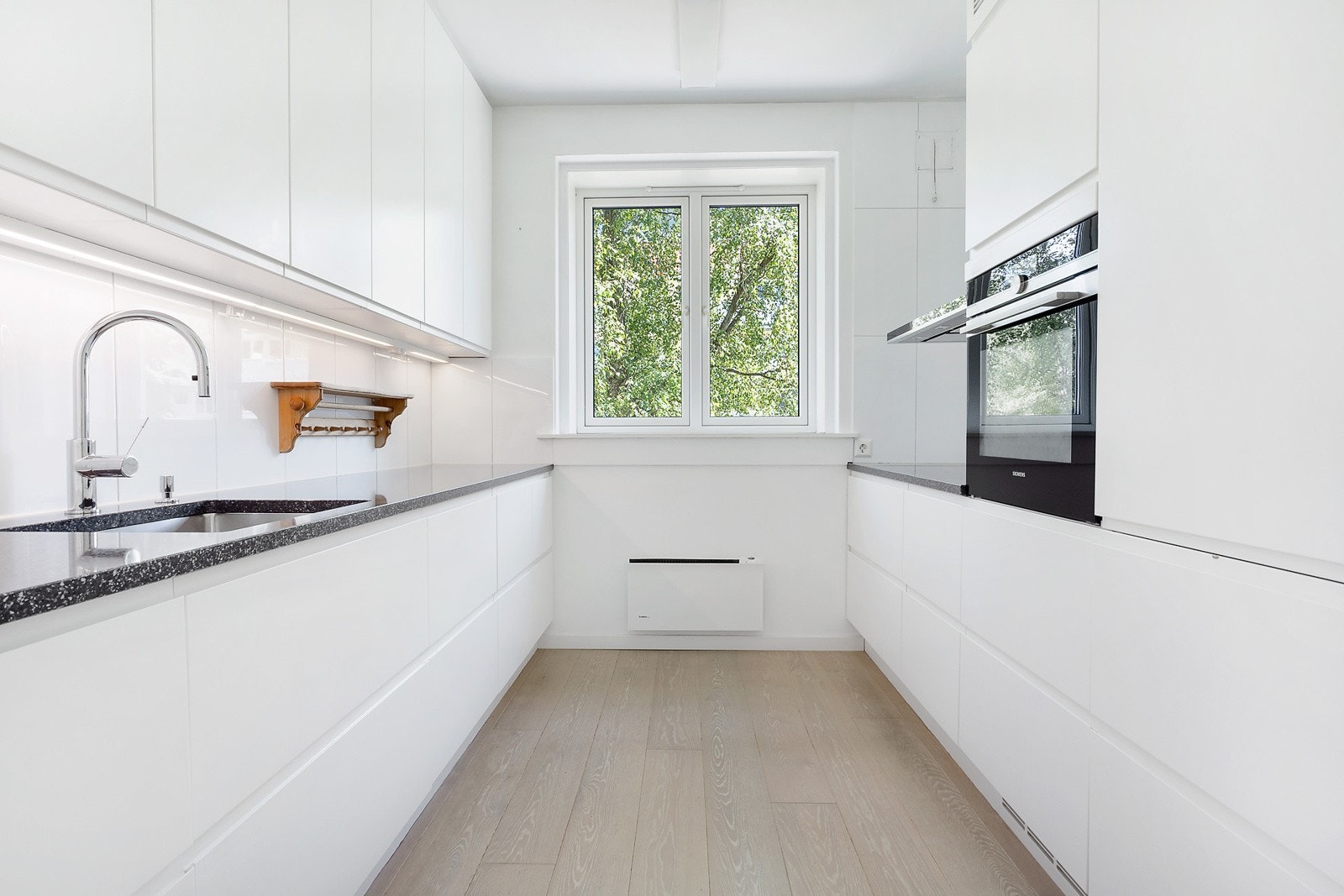 Kjøkkeninnredning fra 2016 med slette fronter. Benkeplater av stein. Underlimt oppvaskkum i rustfritt stål med ett-greps armatur. Galleribilde