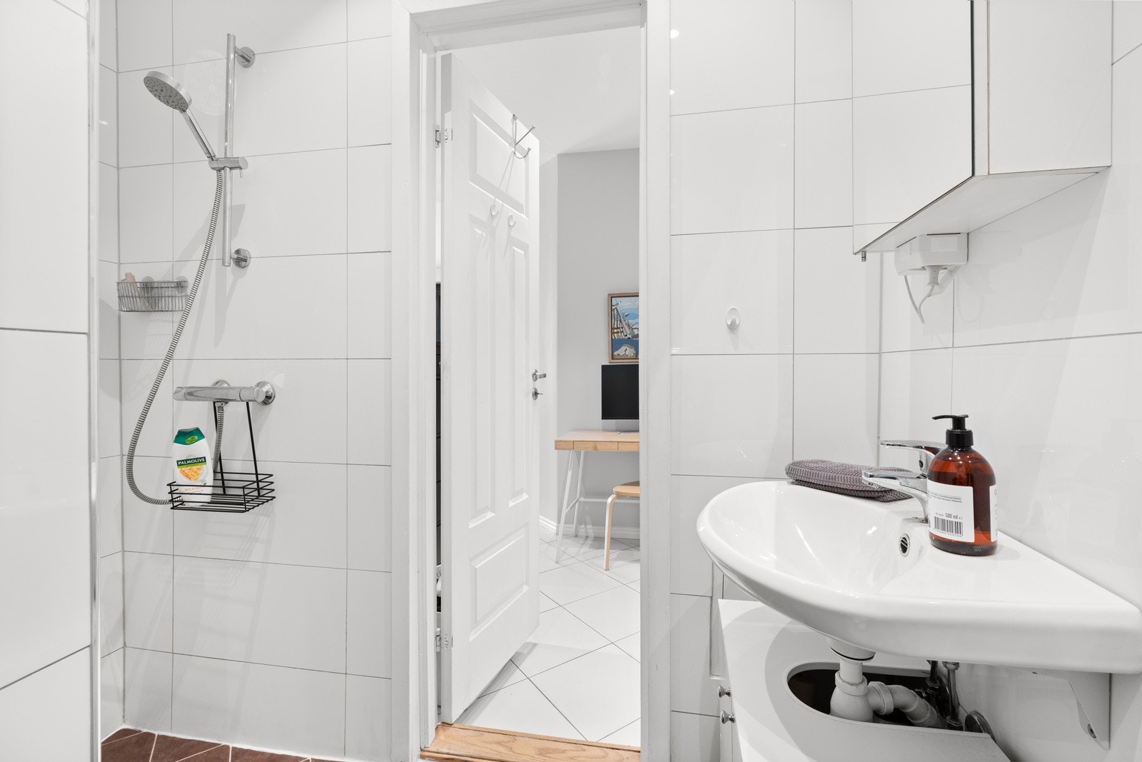 Badet har servant med underskap, speilskap på vegg over servant, dushjørne og vegghengt toalett. Galleribilde