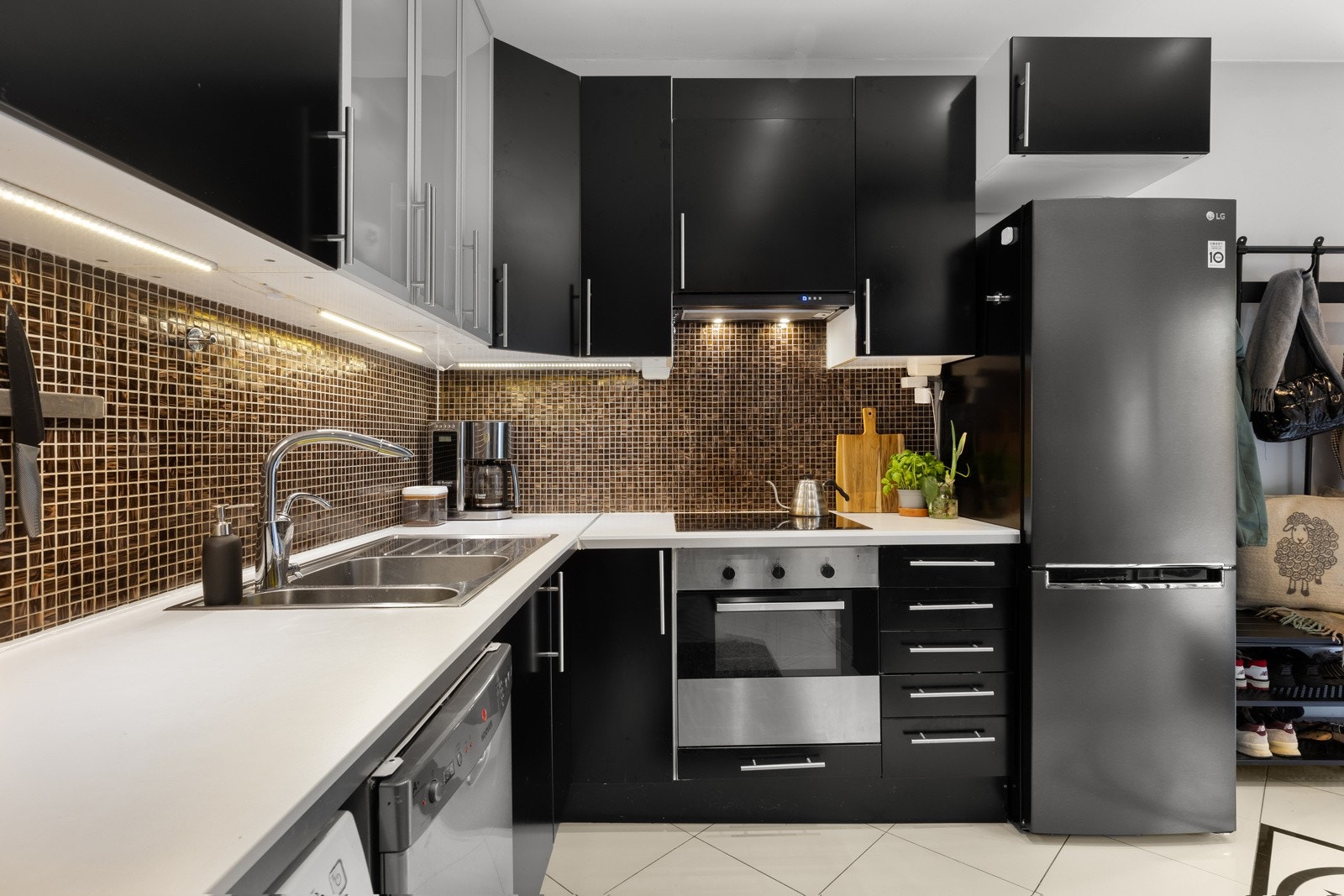 Kjøkkenet har en praktisk og fin innredning fra IKEA med mørke fronter og fliser over benkeplate av laminat. Galleribilde