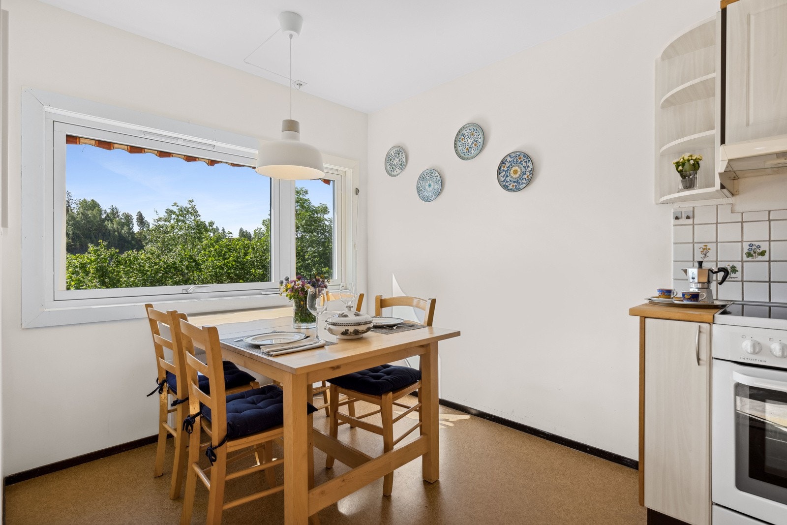 Lyst og hyggelig kjøkken med fin spiseplass ved vindu Galleribilde