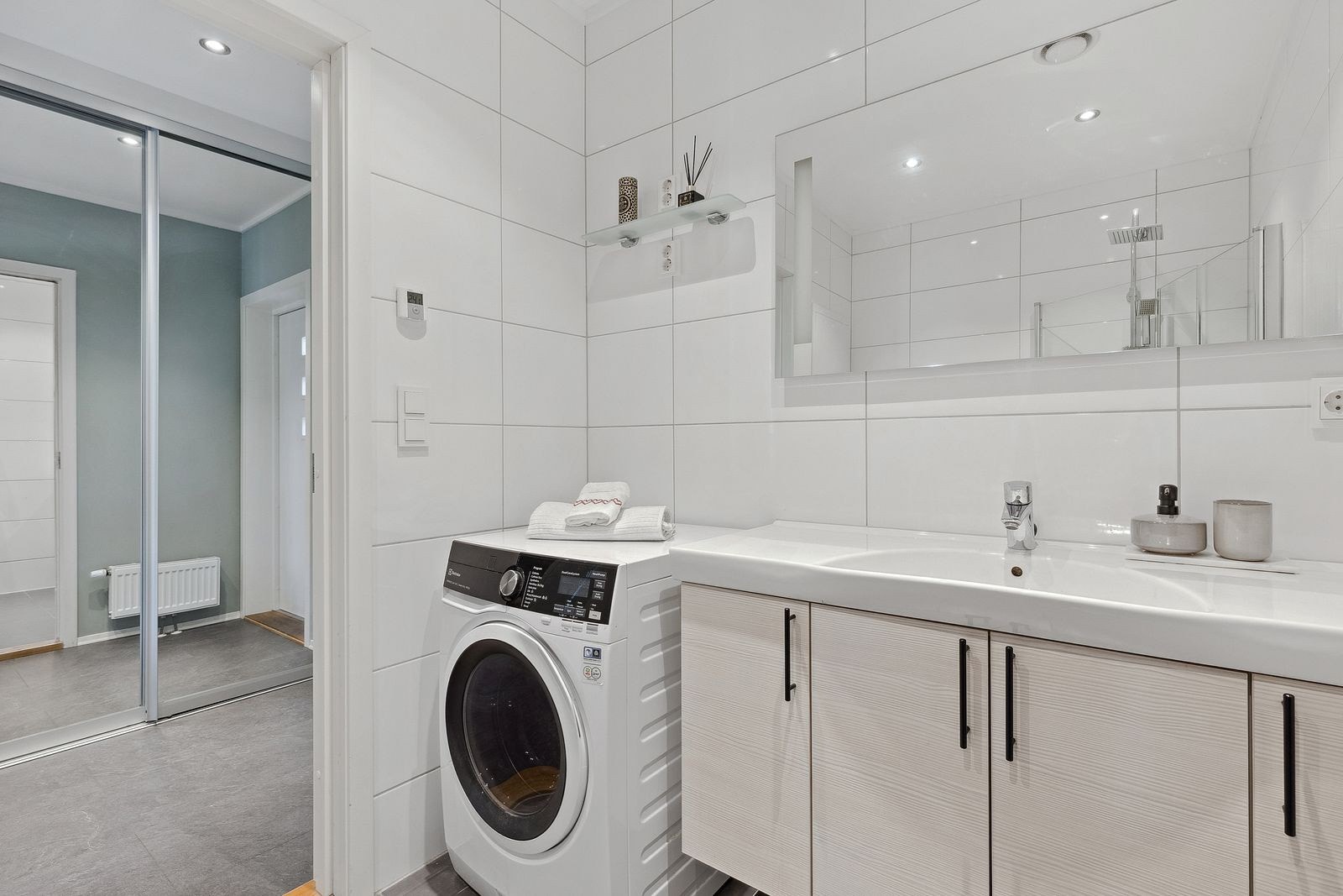 Badet er utstyrt med opplegg for vaskemaskin, innfellbare dusjdører, veggmontert wc og servantskap. Galleribilde