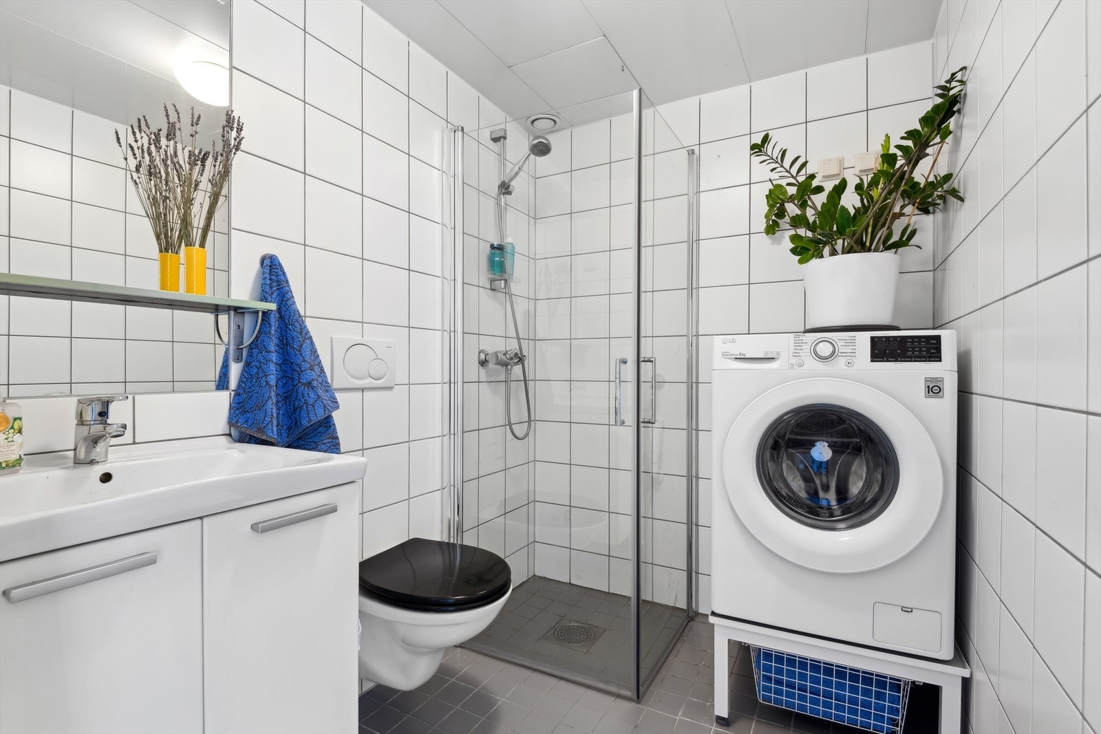 Pent bad med grå fliser på gulv og hvite fliser på vegger, samt behagelig varme i gulv. Det er opplegg til vaskemaskin og plass til tørketrommel. Galleribilde