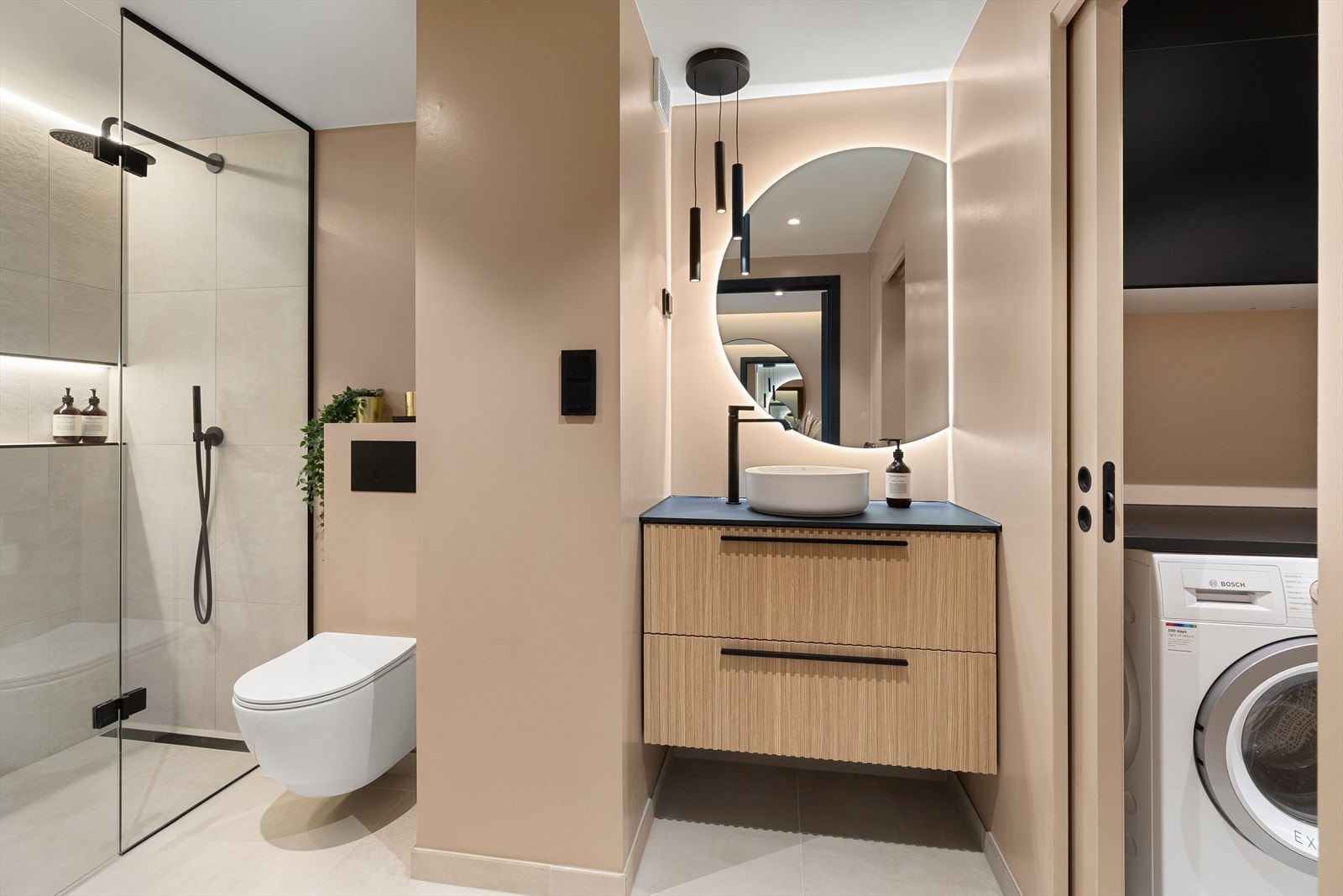 Badet inneholder dusjsone, vegghengt toalett, servant med underskap og overspeil med belysning Galleribilde