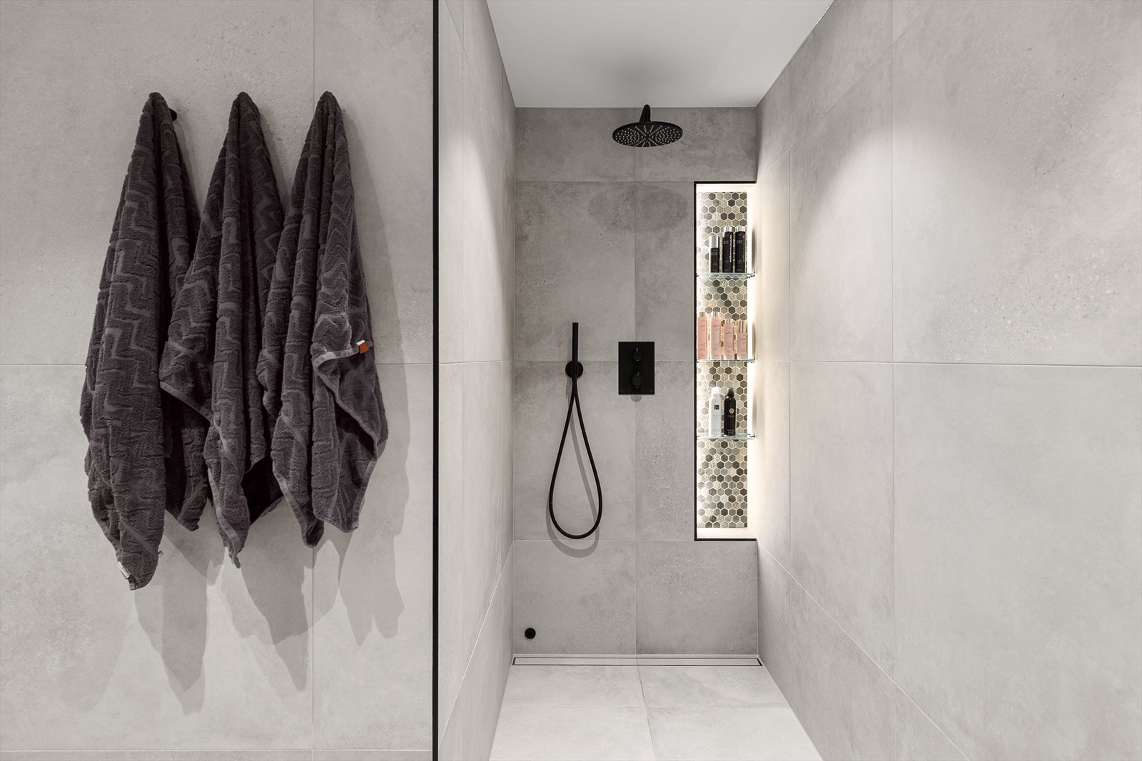 Her har man dusjsone, badekar, vegghengt klosett samt servant med underskap og overspeil med integrerte belysning Galleribilde