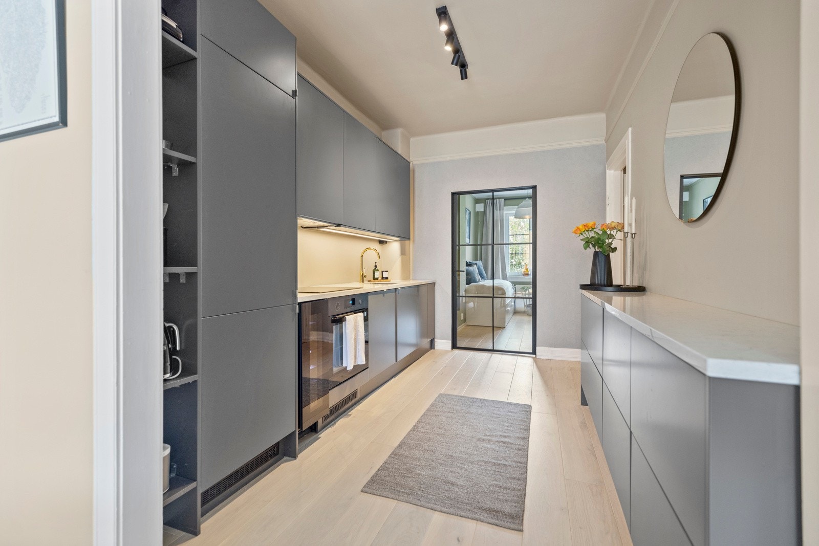 Det hele gjøres komplett med lekre benkeplater av lys stein, underlimt oppvaskkum av kompositt og ettgreps blandebatteri i forgylt utførelse Galleribilde