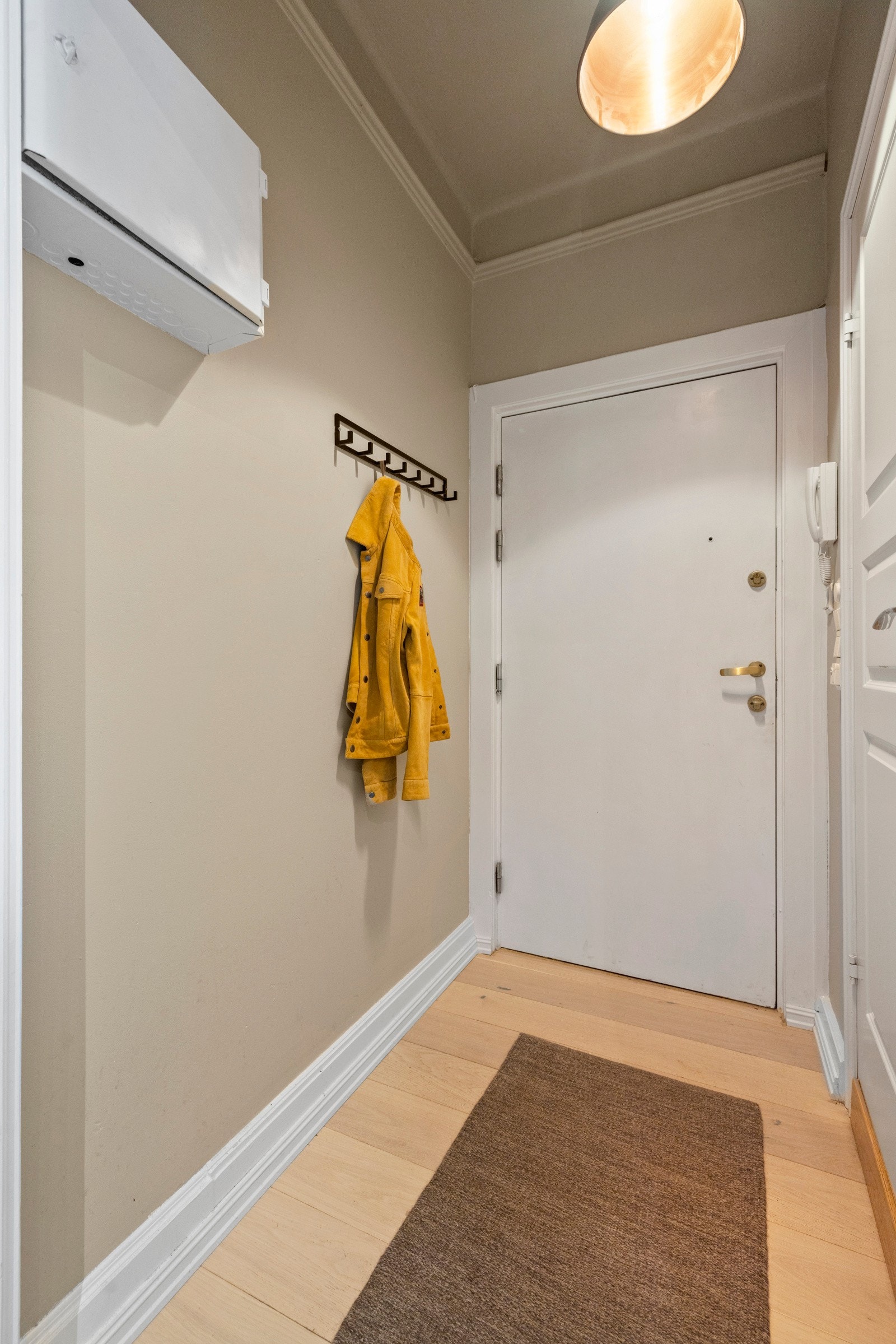 I entréen er det dørcalling ved ytterdøren og en knaggrekke montert på gråmalte veggflater Galleribilde