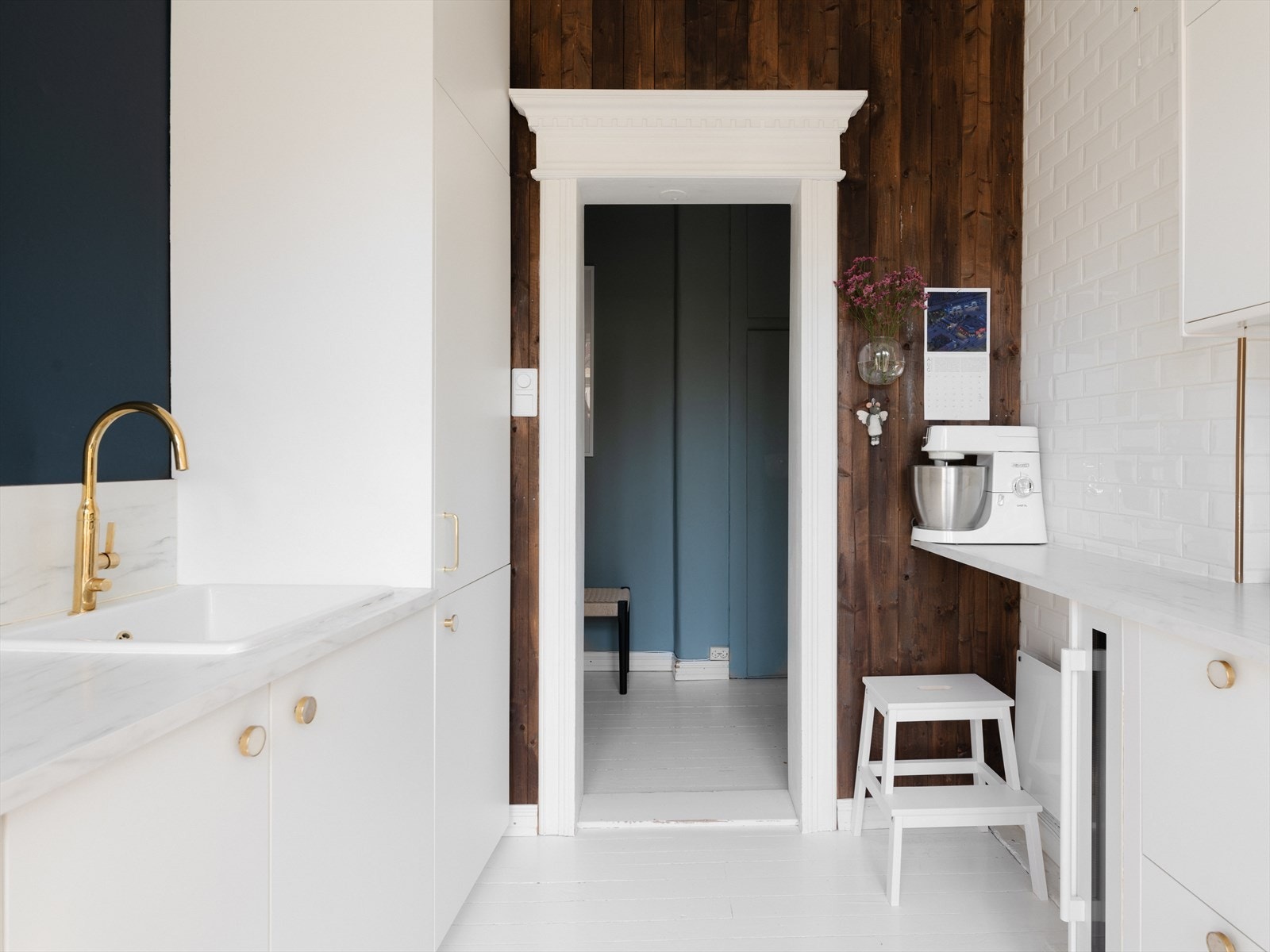 Et nydelig kjøkken med beiset panel, originale tregulv og slette flater over kjøkkenbenken Galleribilde