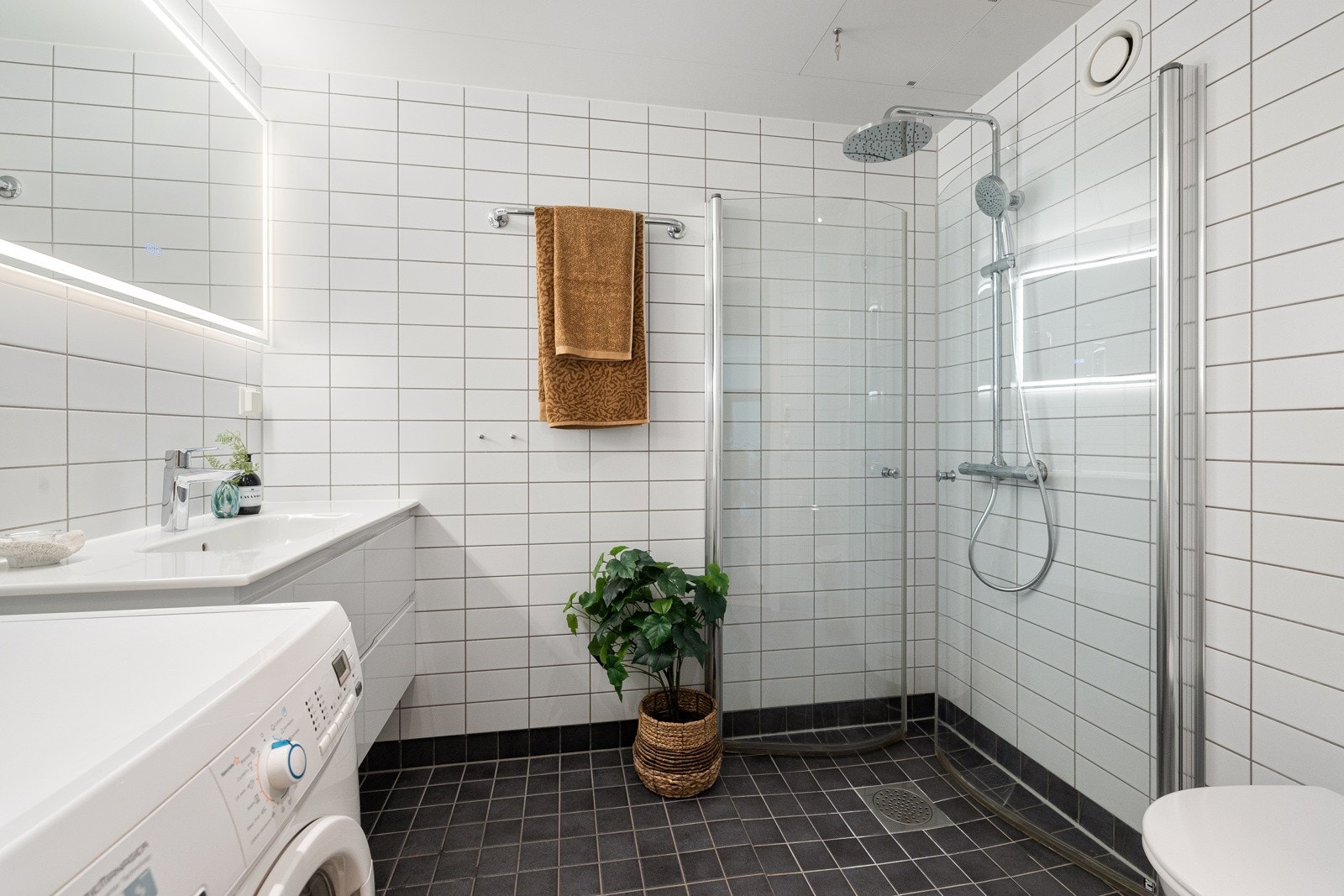 Badet er pent og moderne med varmekabler i gulvet, mørke fliser på gulv og hvite fliser på vegger. Galleribilde