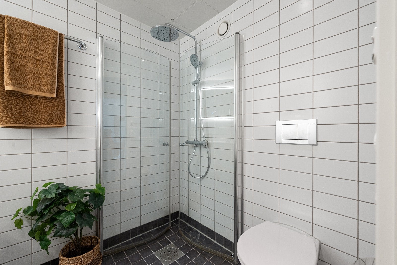 Innredningen består av en heldekkende servant på hvit skuffeseksjon, speil med lys, et veggmontert toalett og et stort dusjhjørne med glassdører. Galleribilde